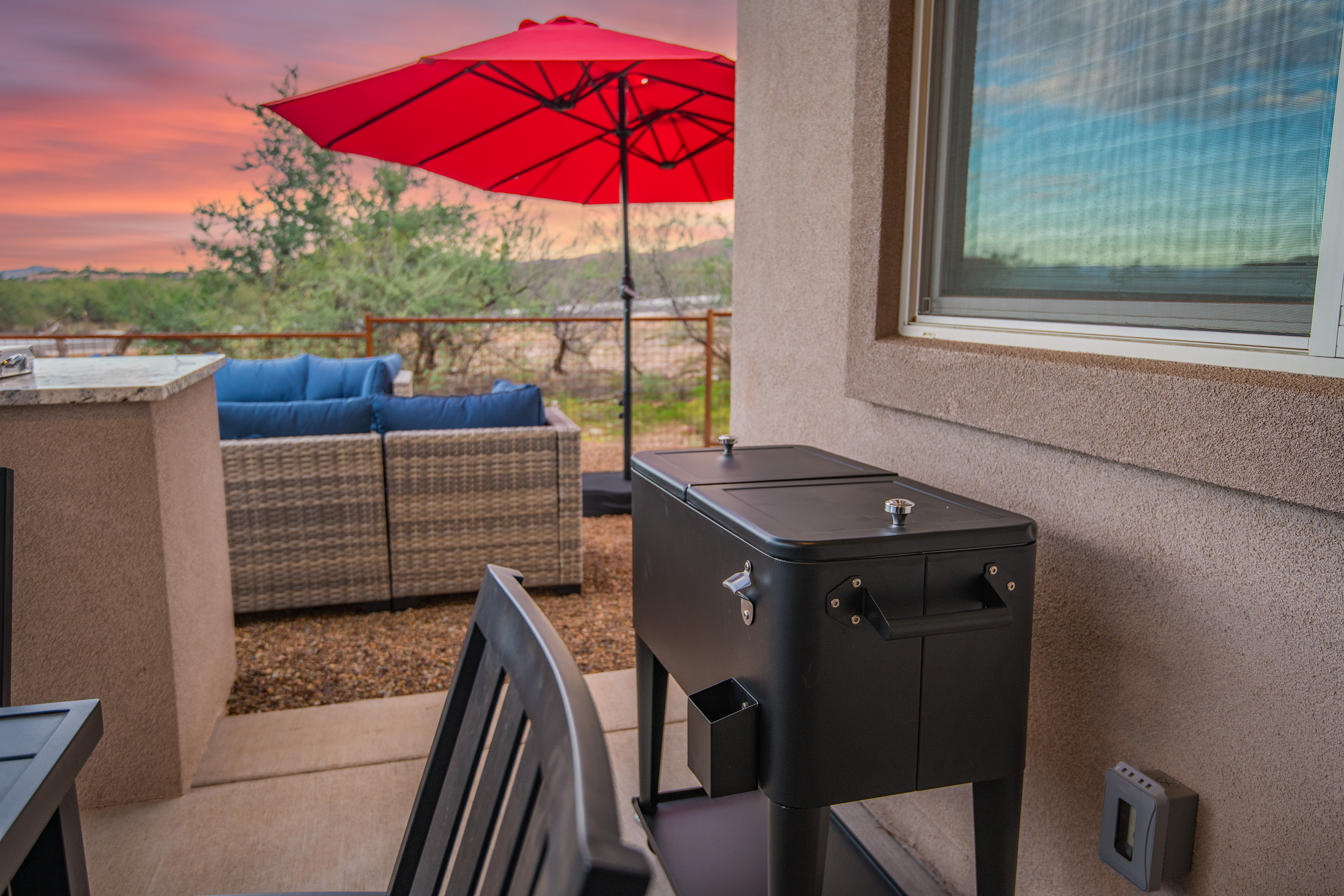 Private patio with grill, lounge seating, and sunset desert views