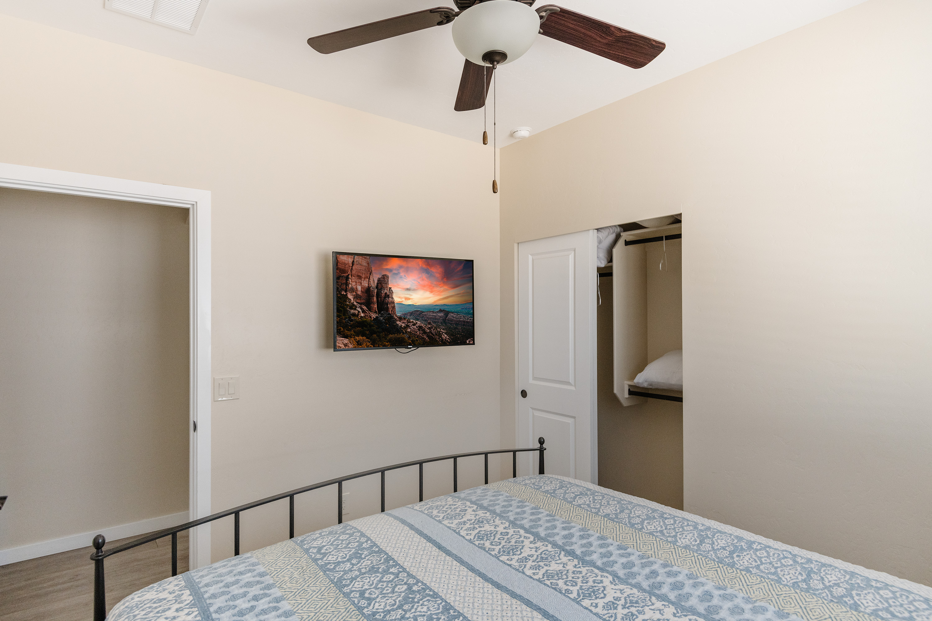 Bright, minimalist bedroom with TV, ceiling fan, and high ceilings