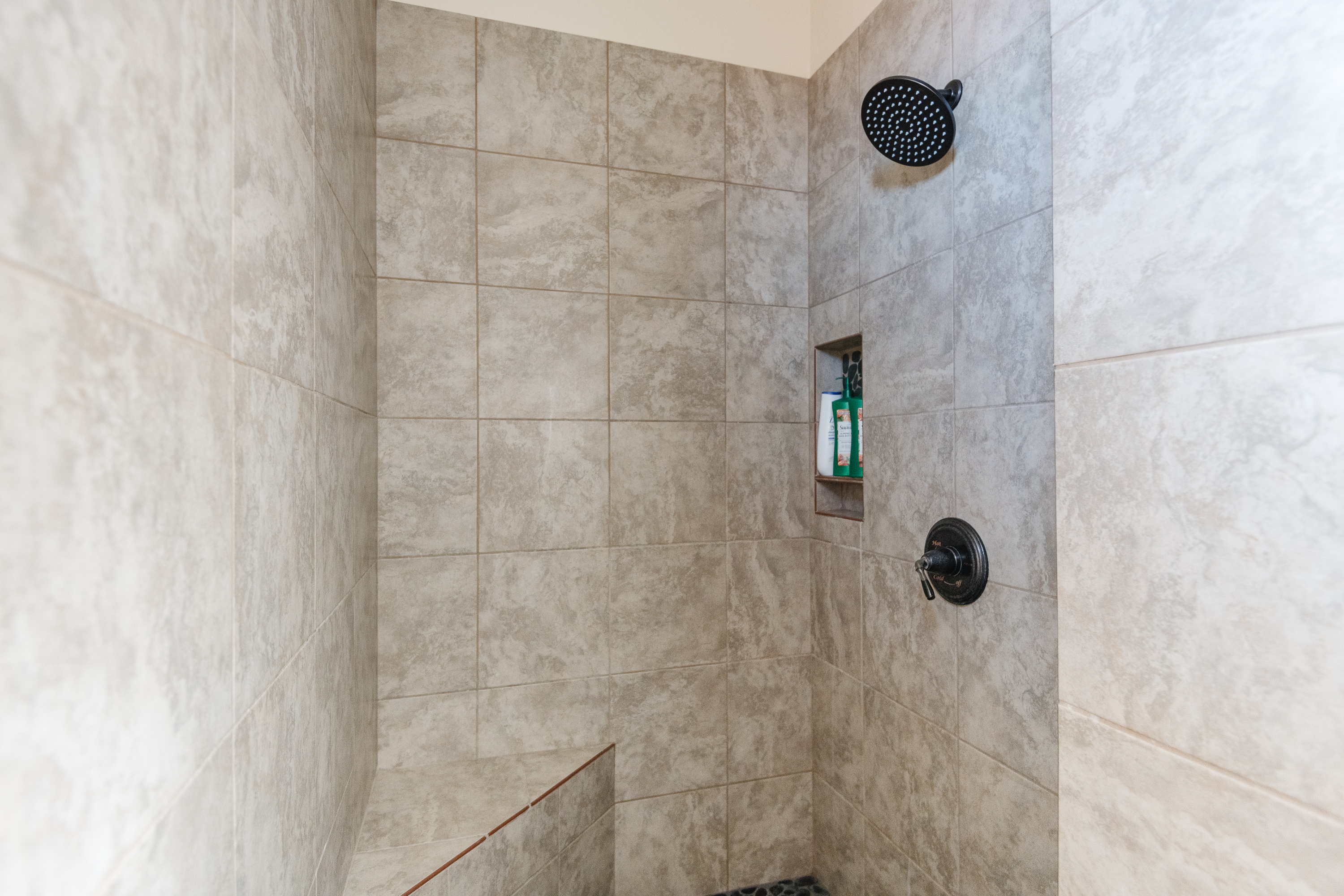 Spacious tiled walk-in shower with rainfall head and built-in niche