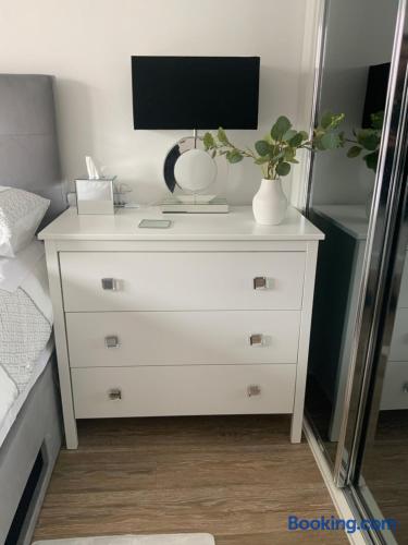 Modern bedroom with dresser, TV, and mirrored closet