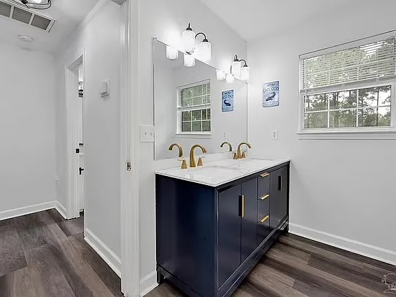 Bright modern bath with double vanity, gold accents, and natural light