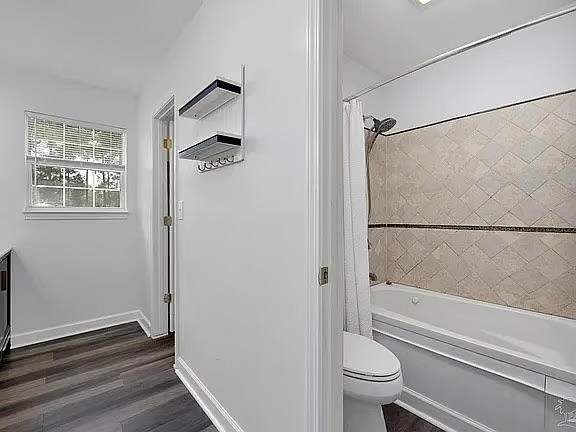 Bright bath with tiled tub-shower and stylish wood-look flooring