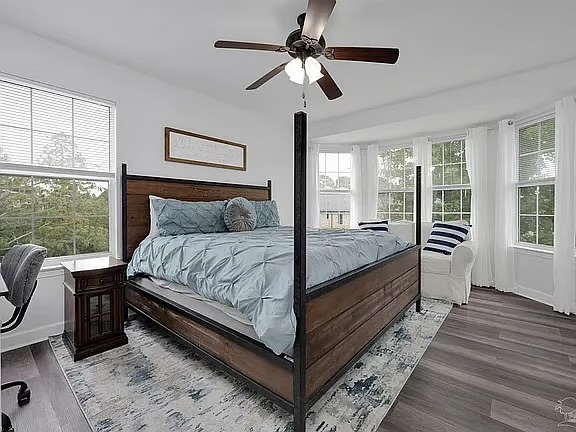 Bright primary bedroom with four-poster bed and sunny window seating