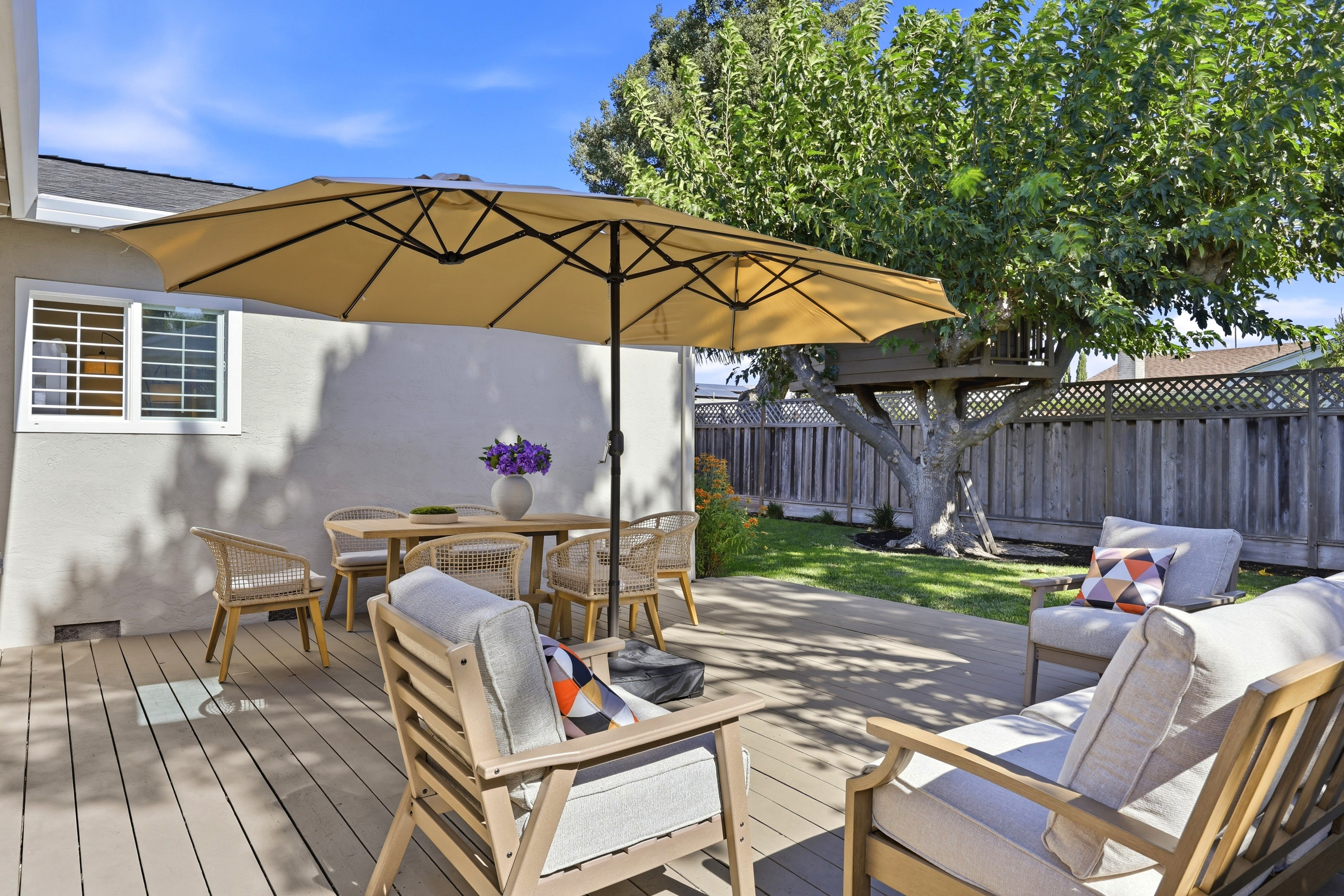 Sunny private backyard patio with shaded dining and cozy lounge seating