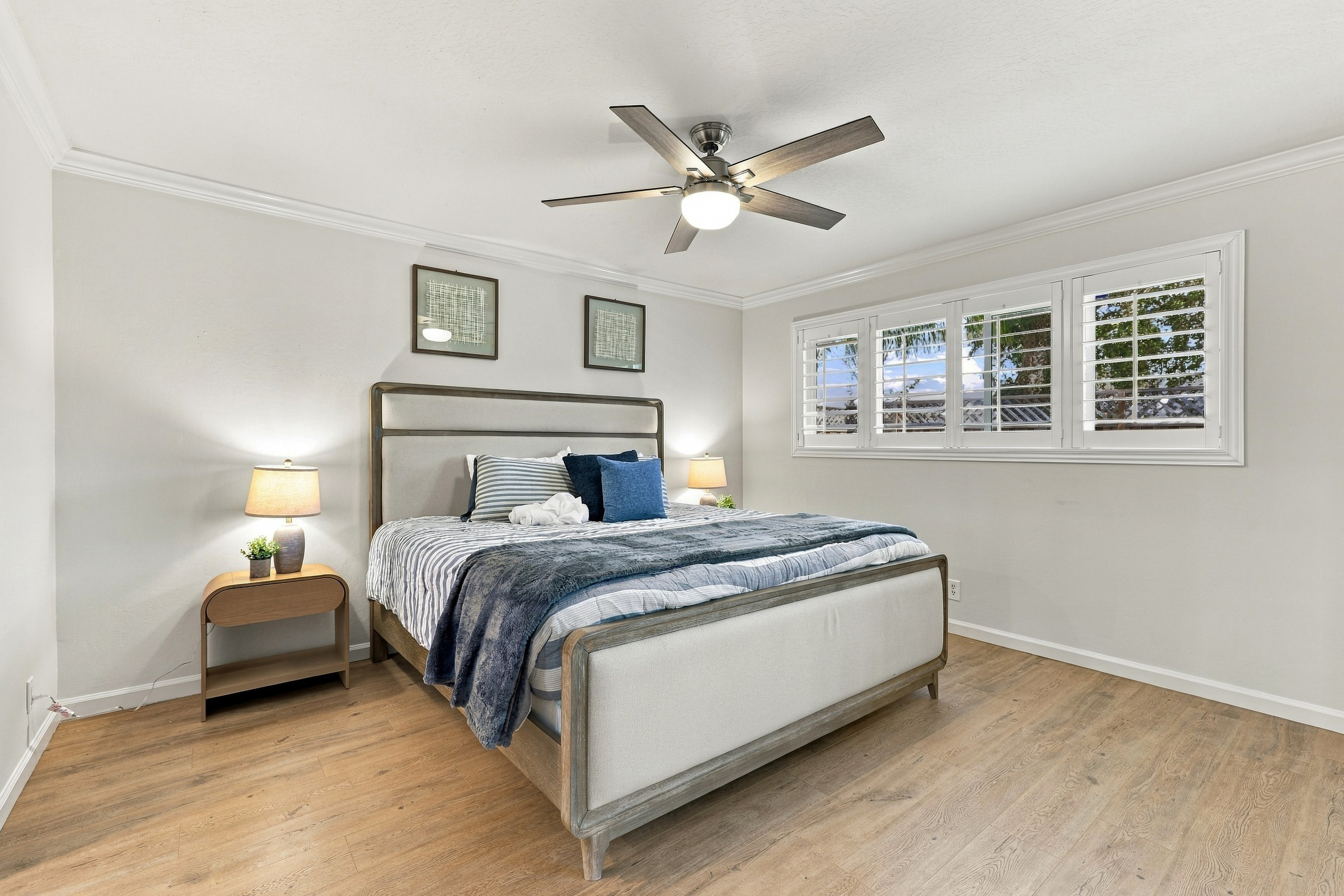 Bright, serene bedroom with shutters, ceiling fan, and modern style