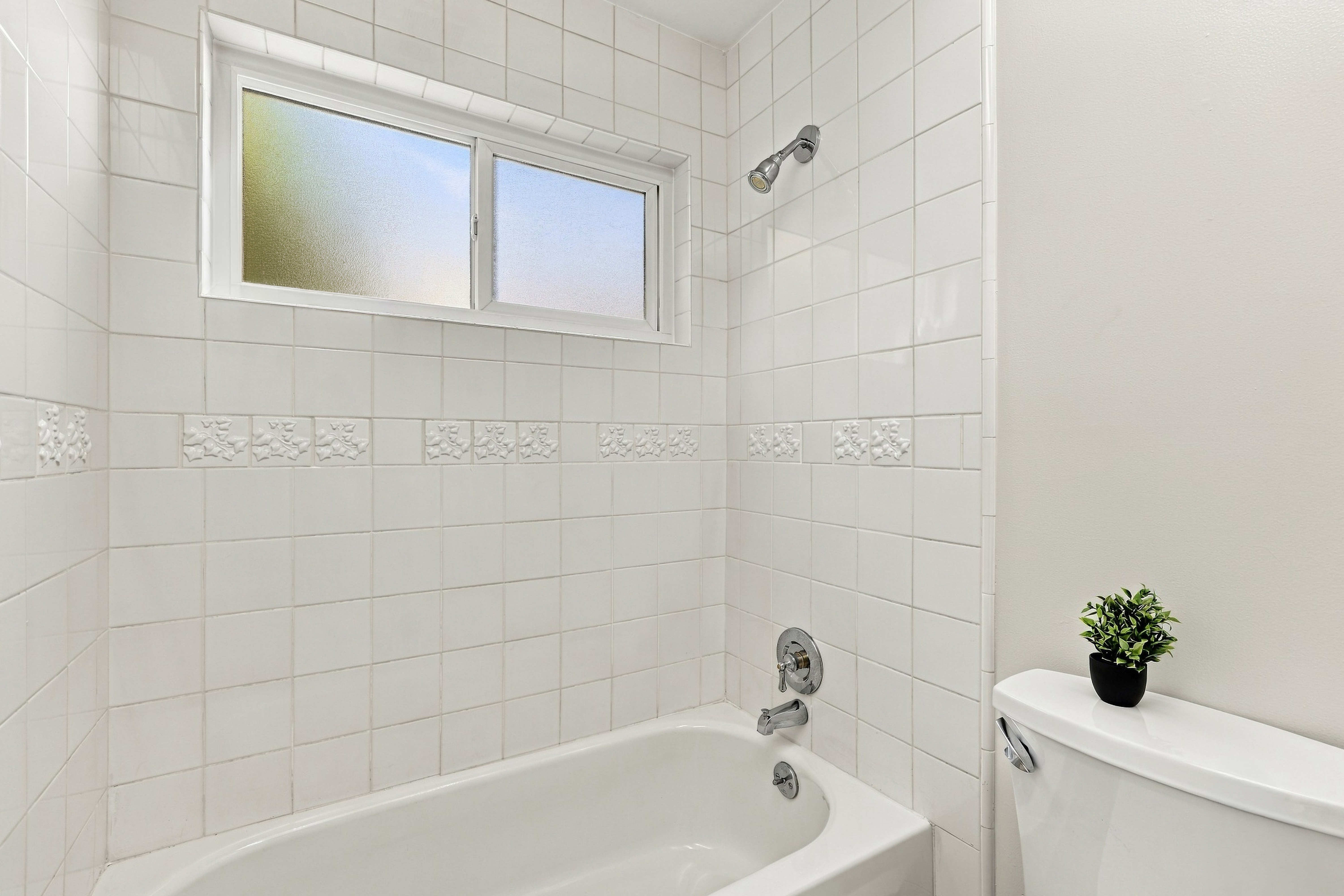 Bright tiled bathroom with tub/shower combo and natural light