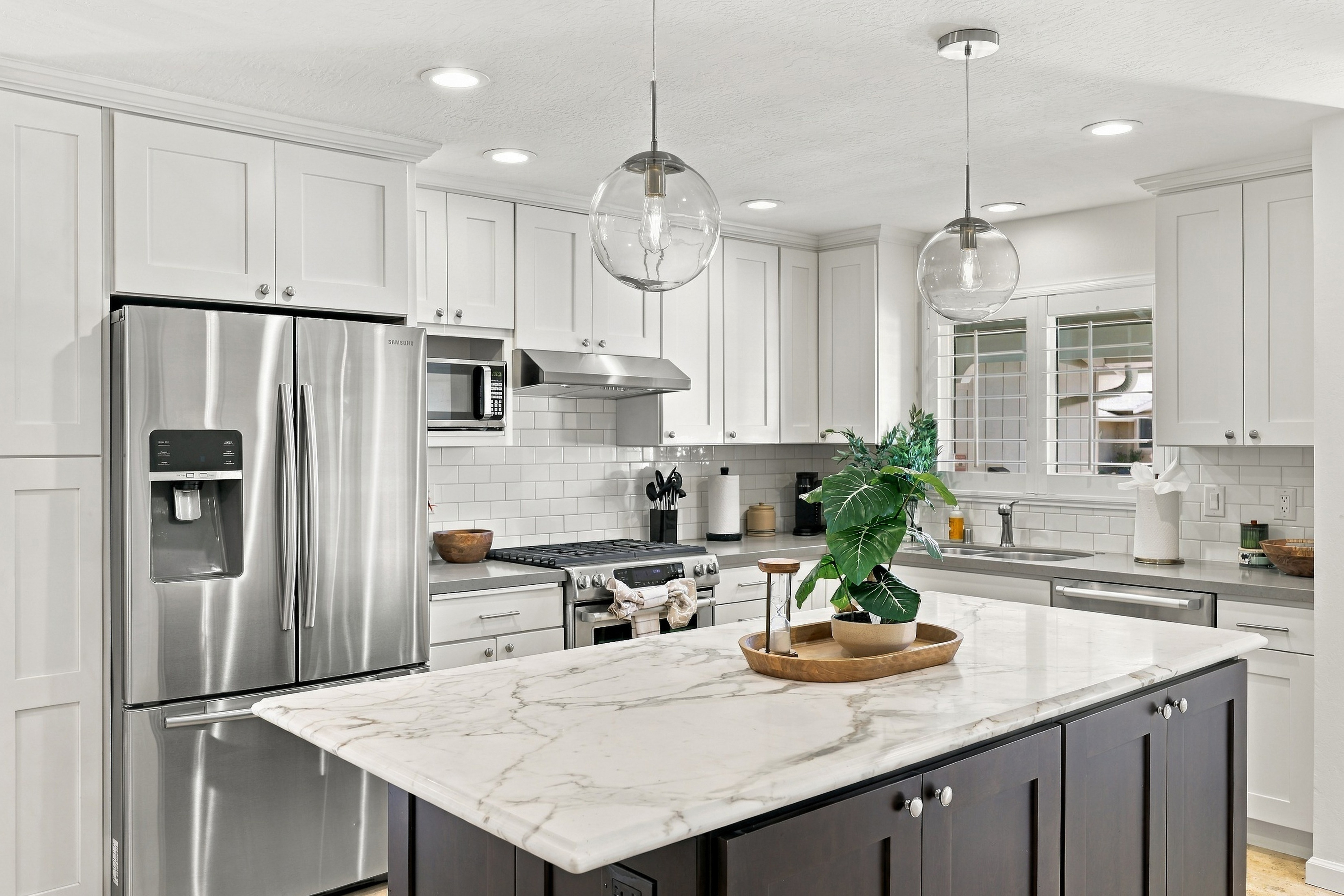 Bright designer kitchen with marble island and stainless steel appliances