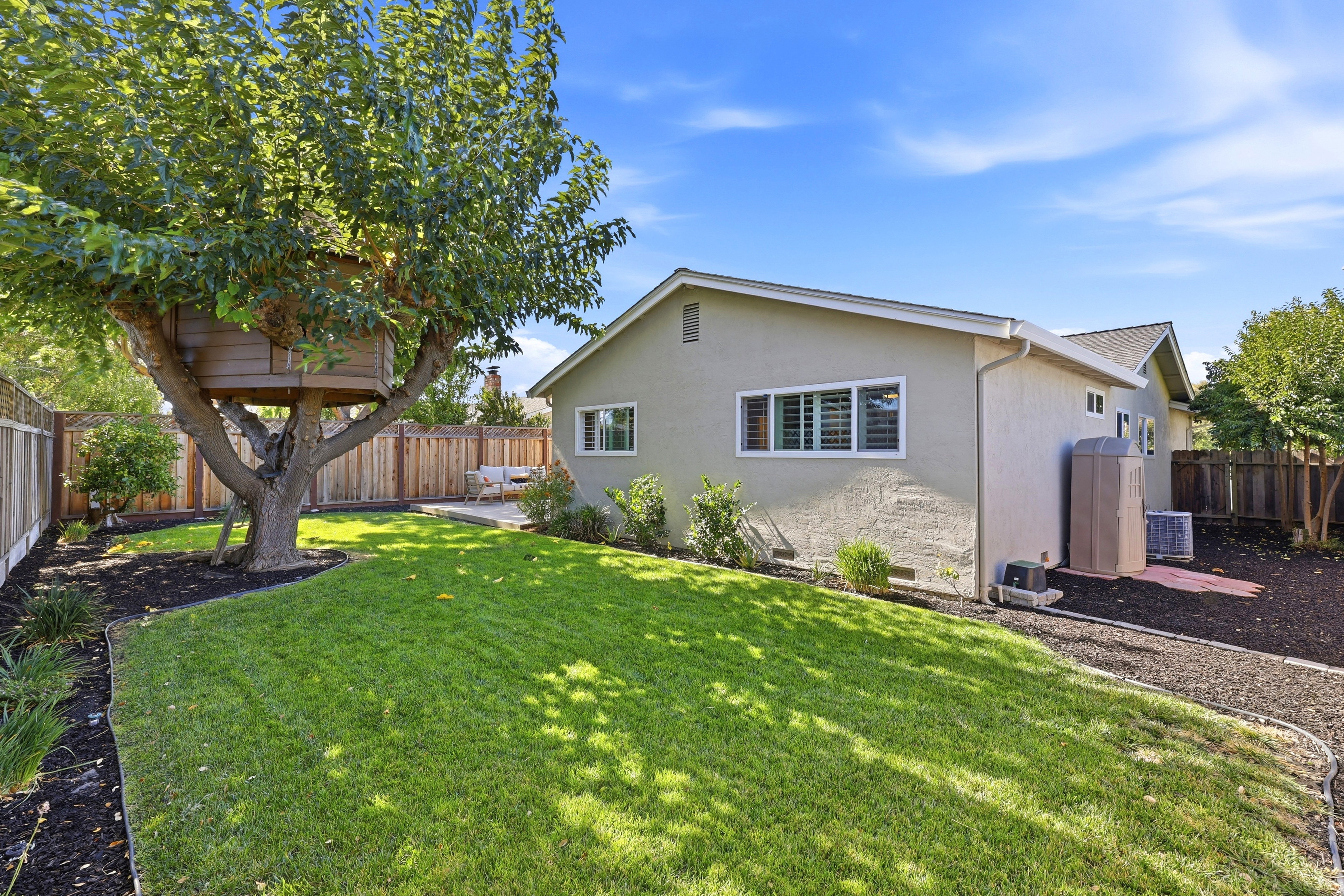 Spacious private backyard with lush lawn and mature shade tree