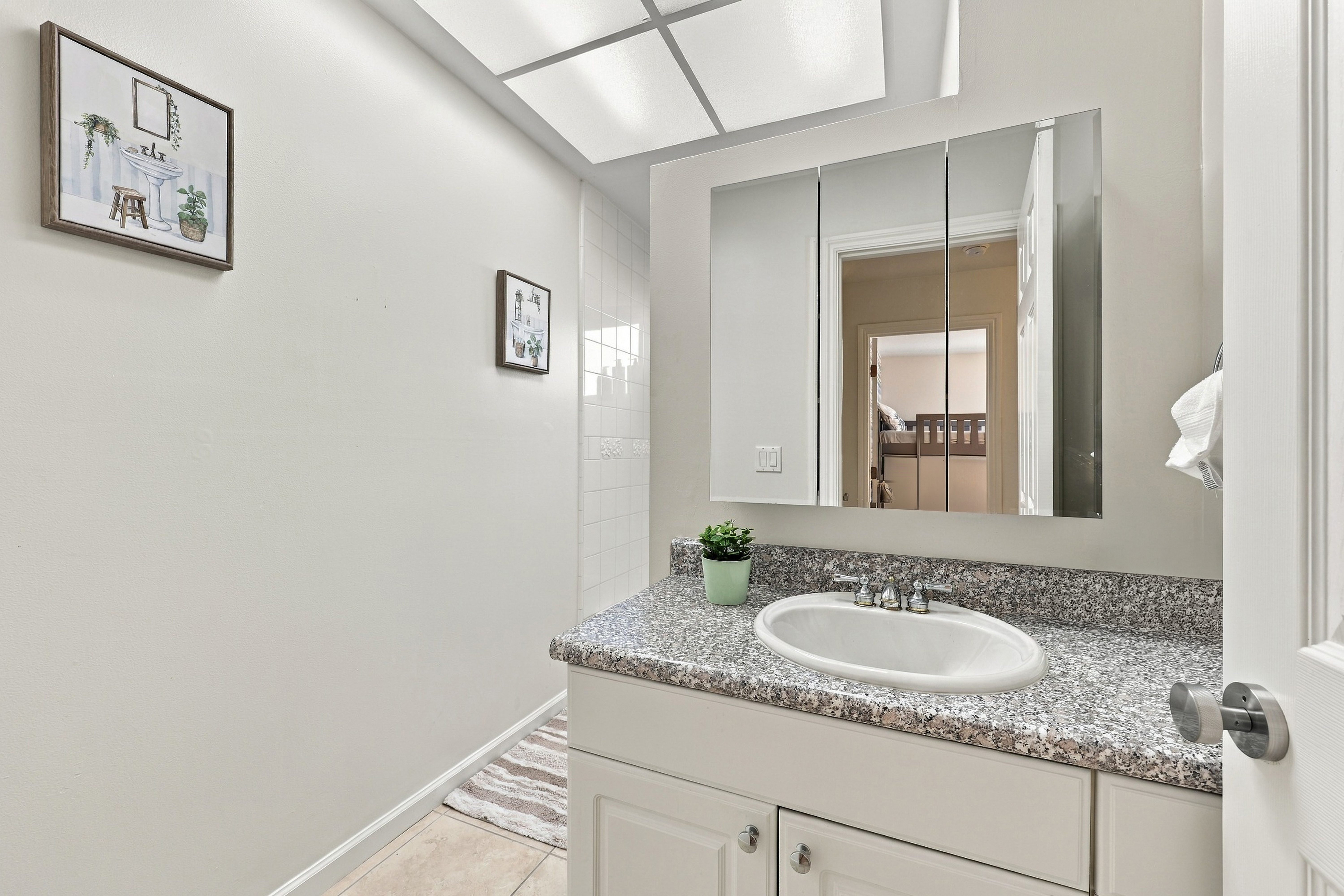 Bright bathroom with granite vanity, great lighting, and mirrored storage