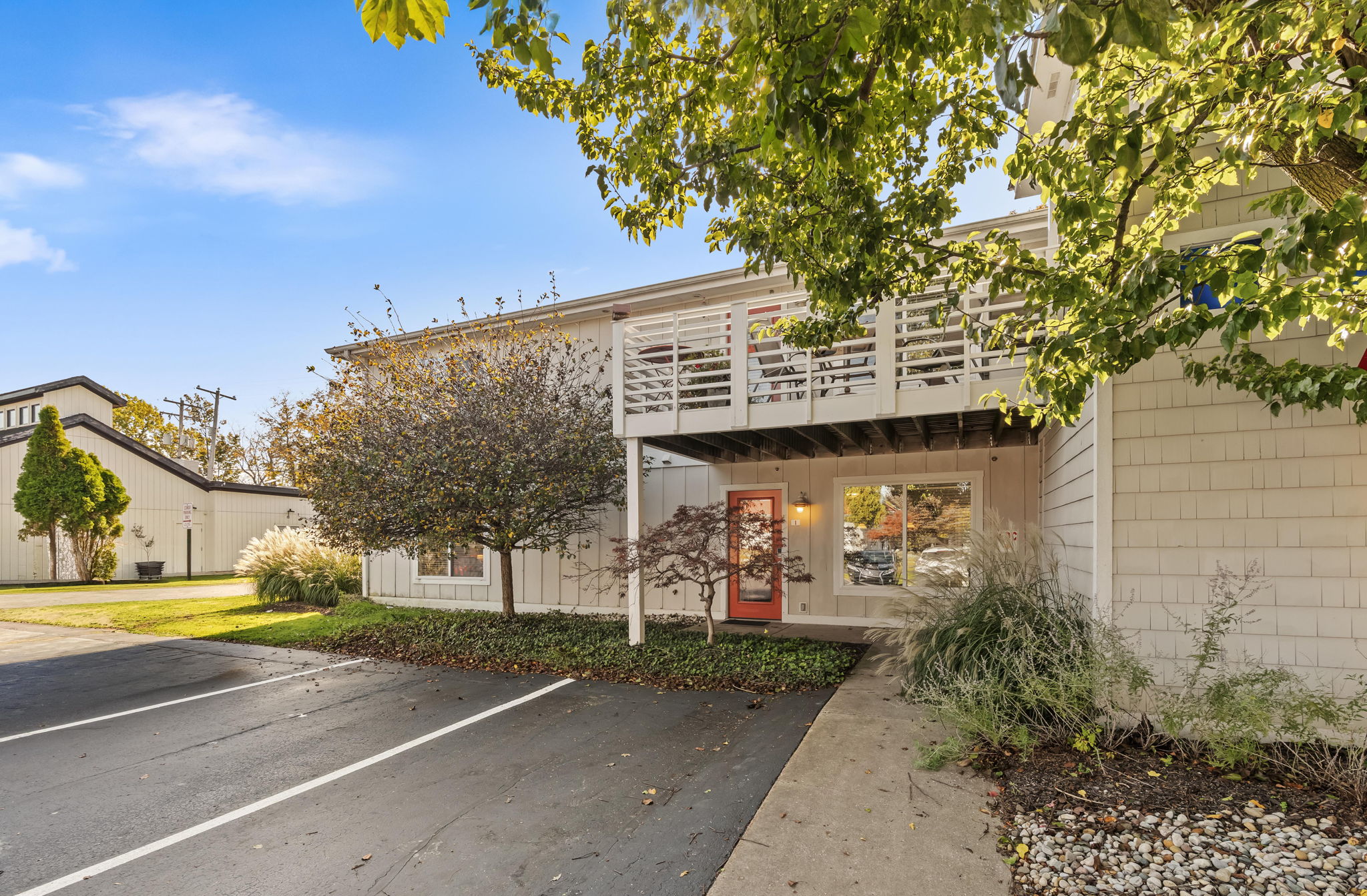 Welcoming townhouse entry with parking, balcony, and lush landscaping