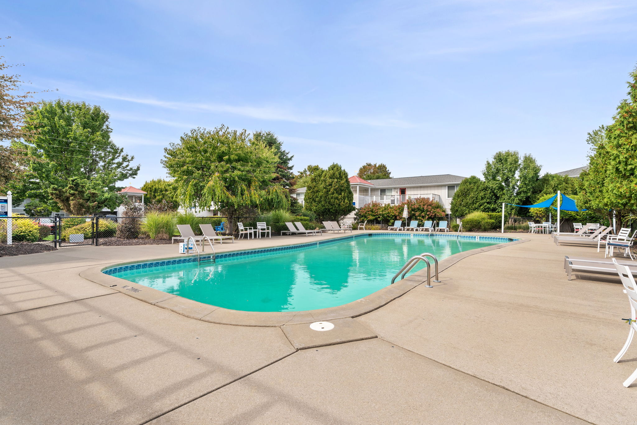 Spacious resort-style pool with sunny deck and shaded lounge seating