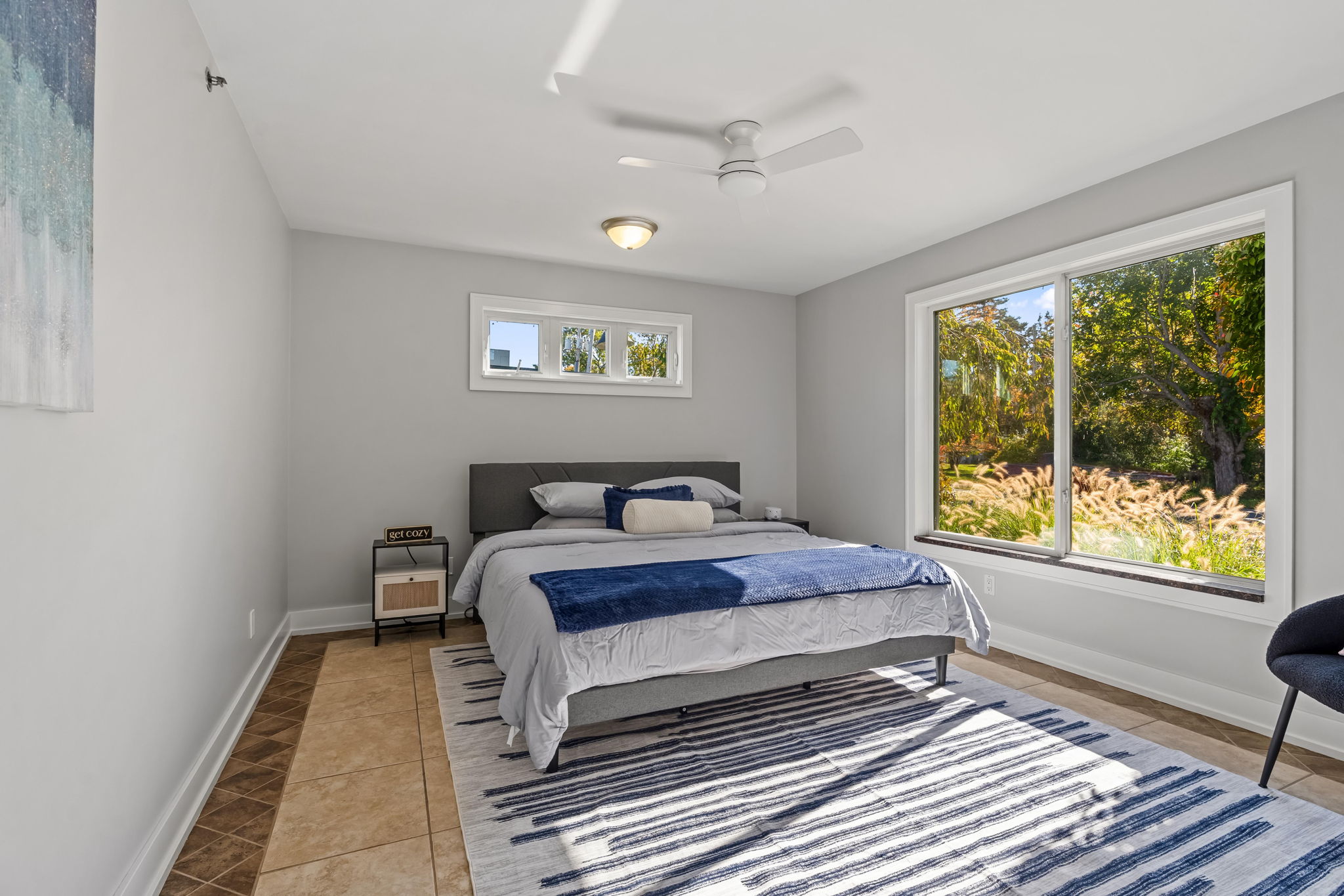 Bright bedroom with large picture window and peaceful garden views