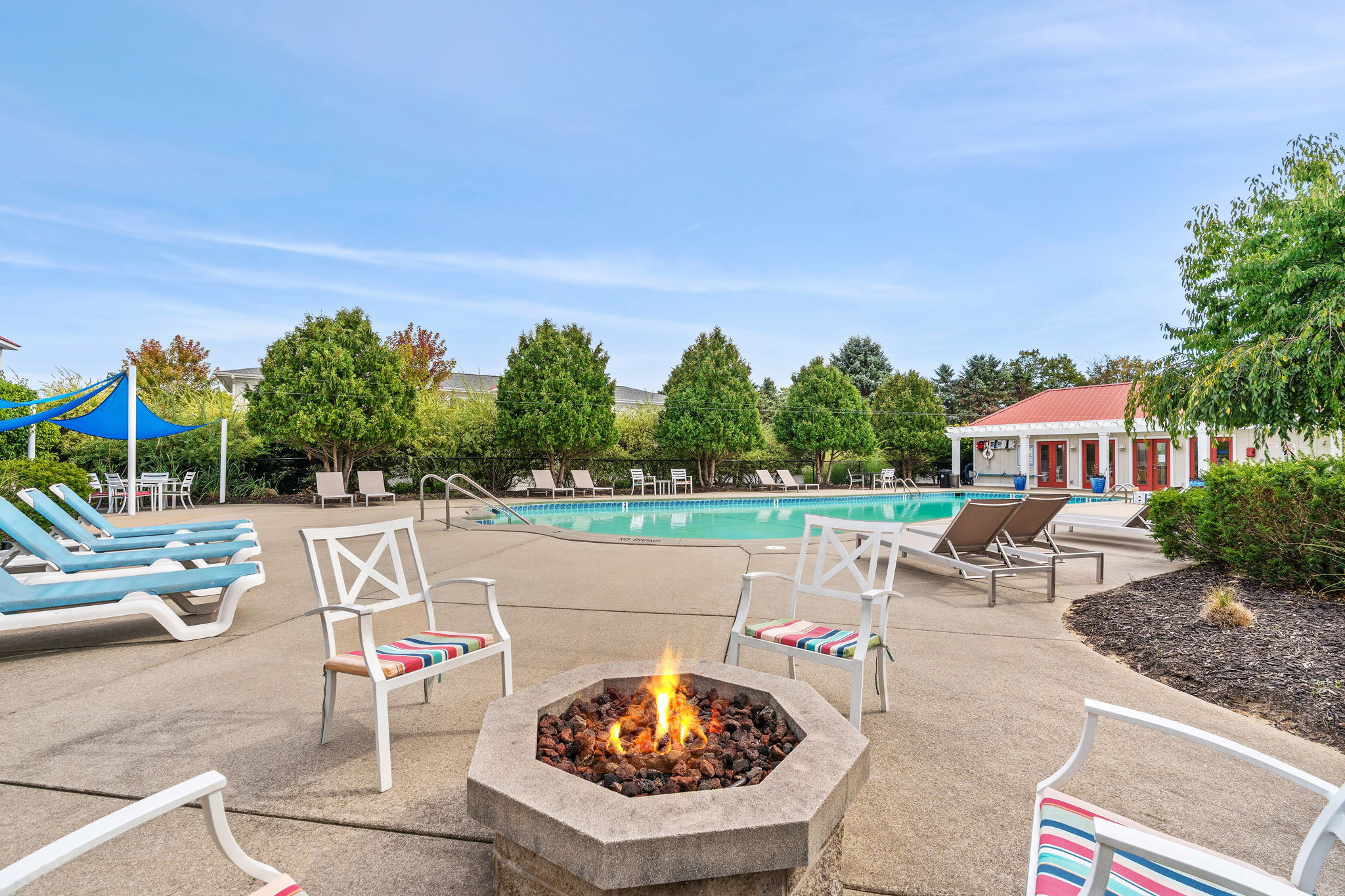 Resort-style pool deck with fire pit, loungers, and relaxing outdoor seating
