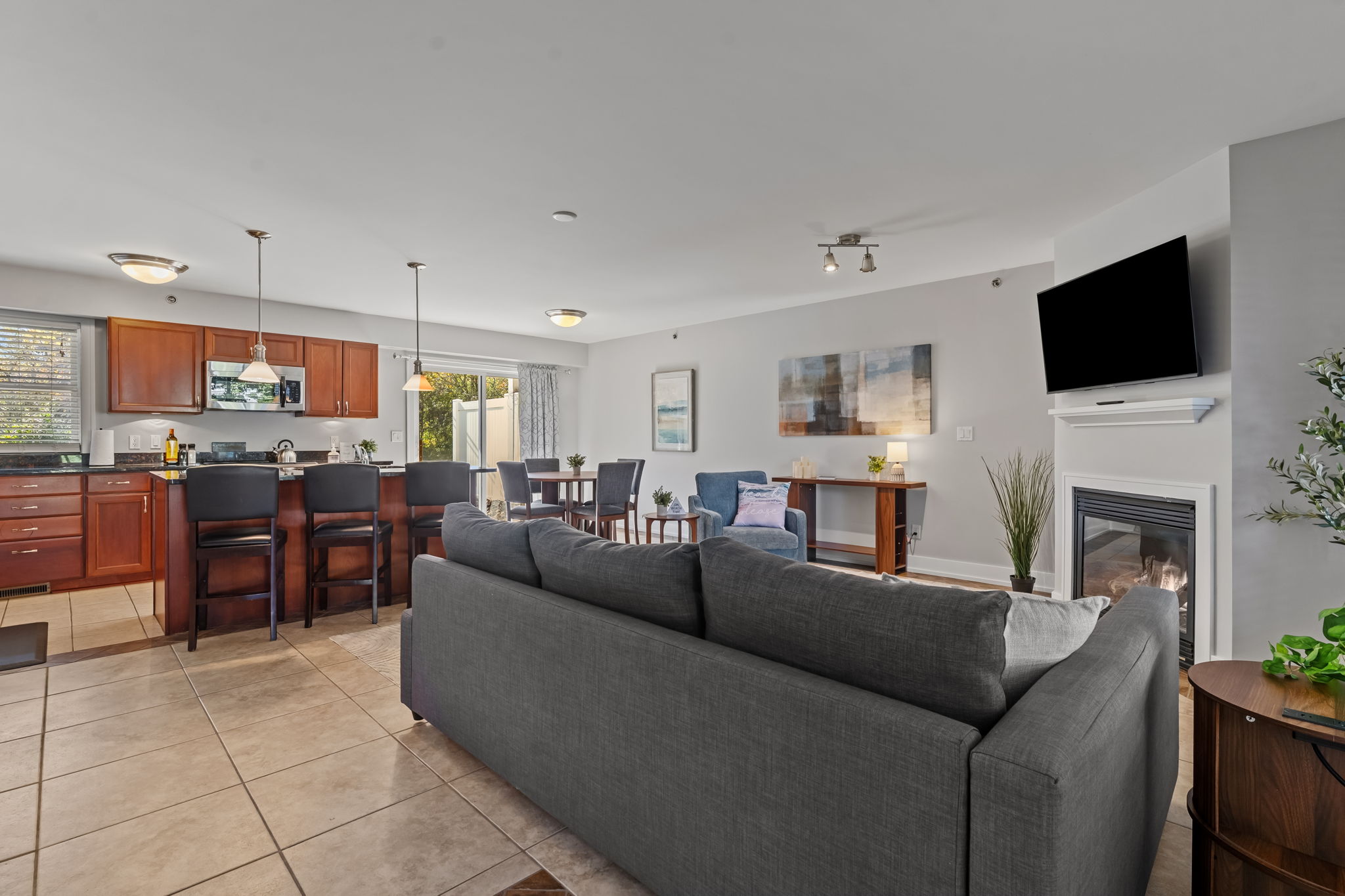 Bright open-concept living space with fireplace, TV, and bar seating