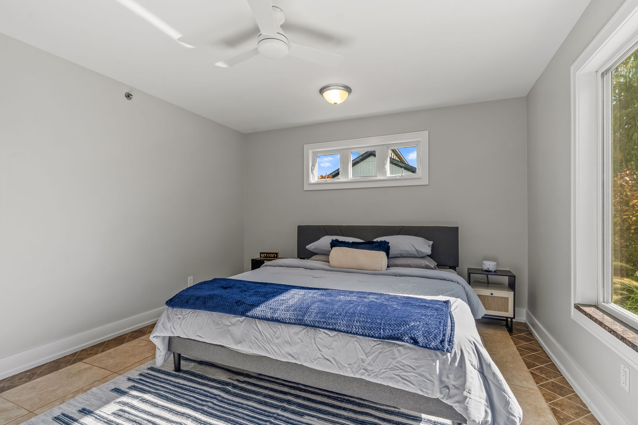 Bright, modern bedroom with natural light, ceiling fan, and cozy king bed