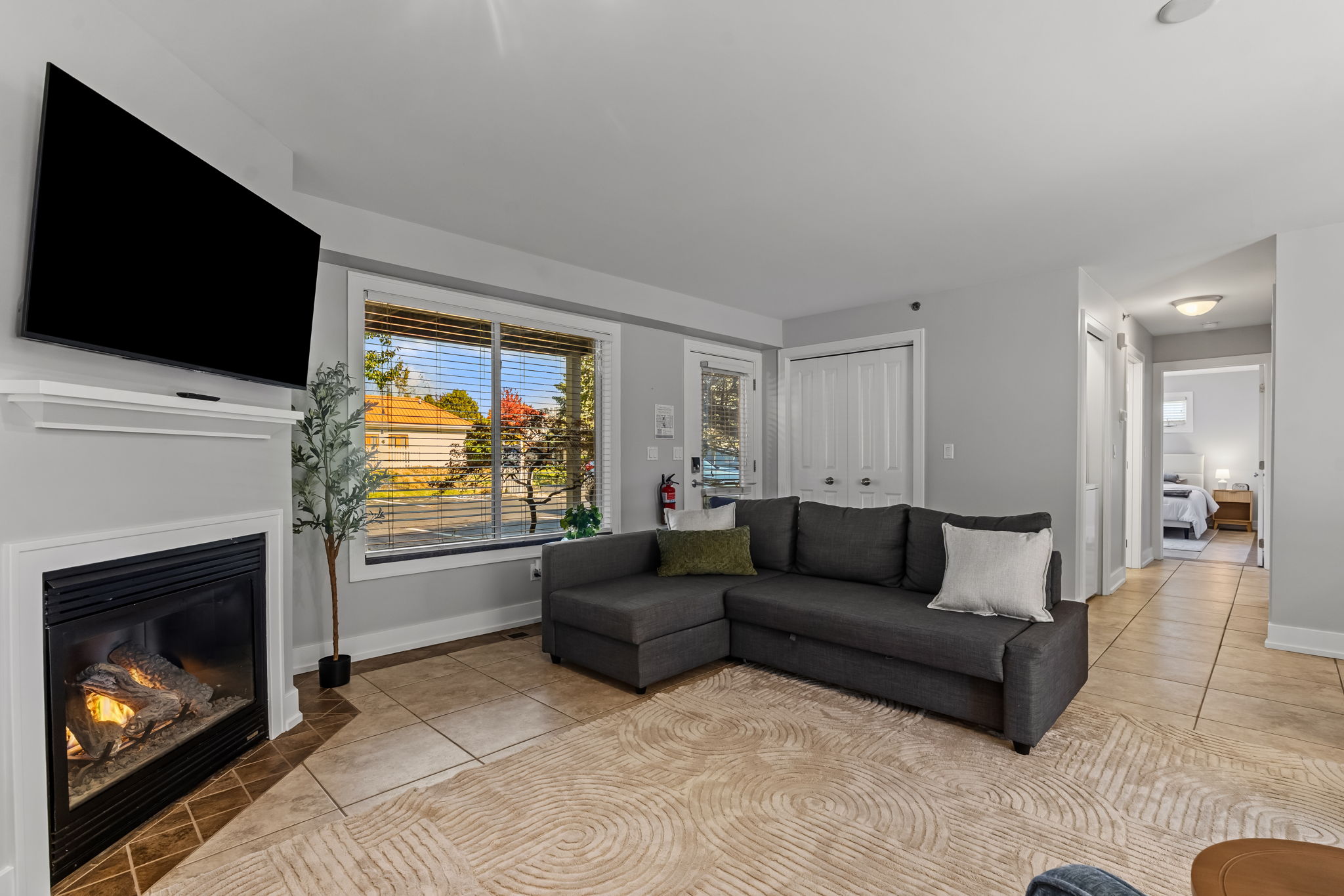 Bright living room with fireplace, large TV, and cozy sectional seating