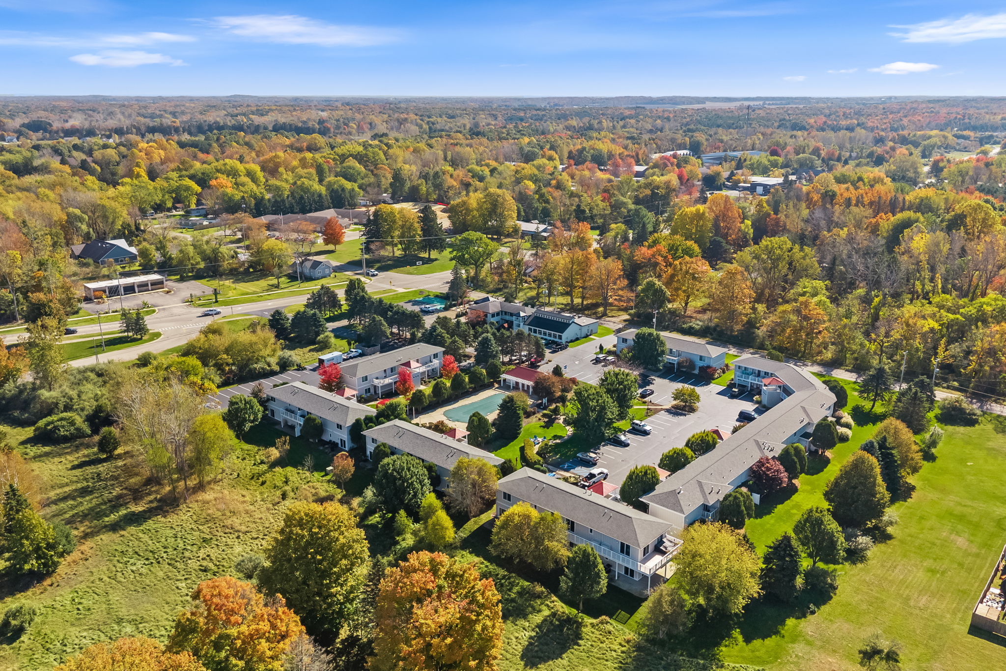 Scenic aerial view with lush grounds, parking, and vibrant fall foliage