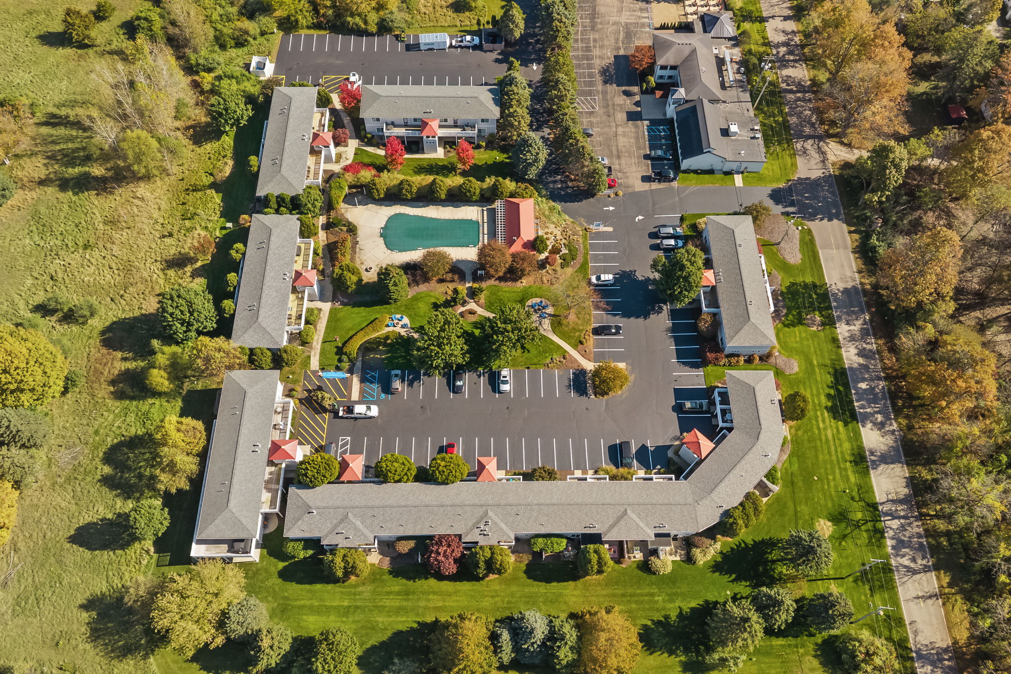 Aerial view with pool, landscaped grounds, and ample on-site parking