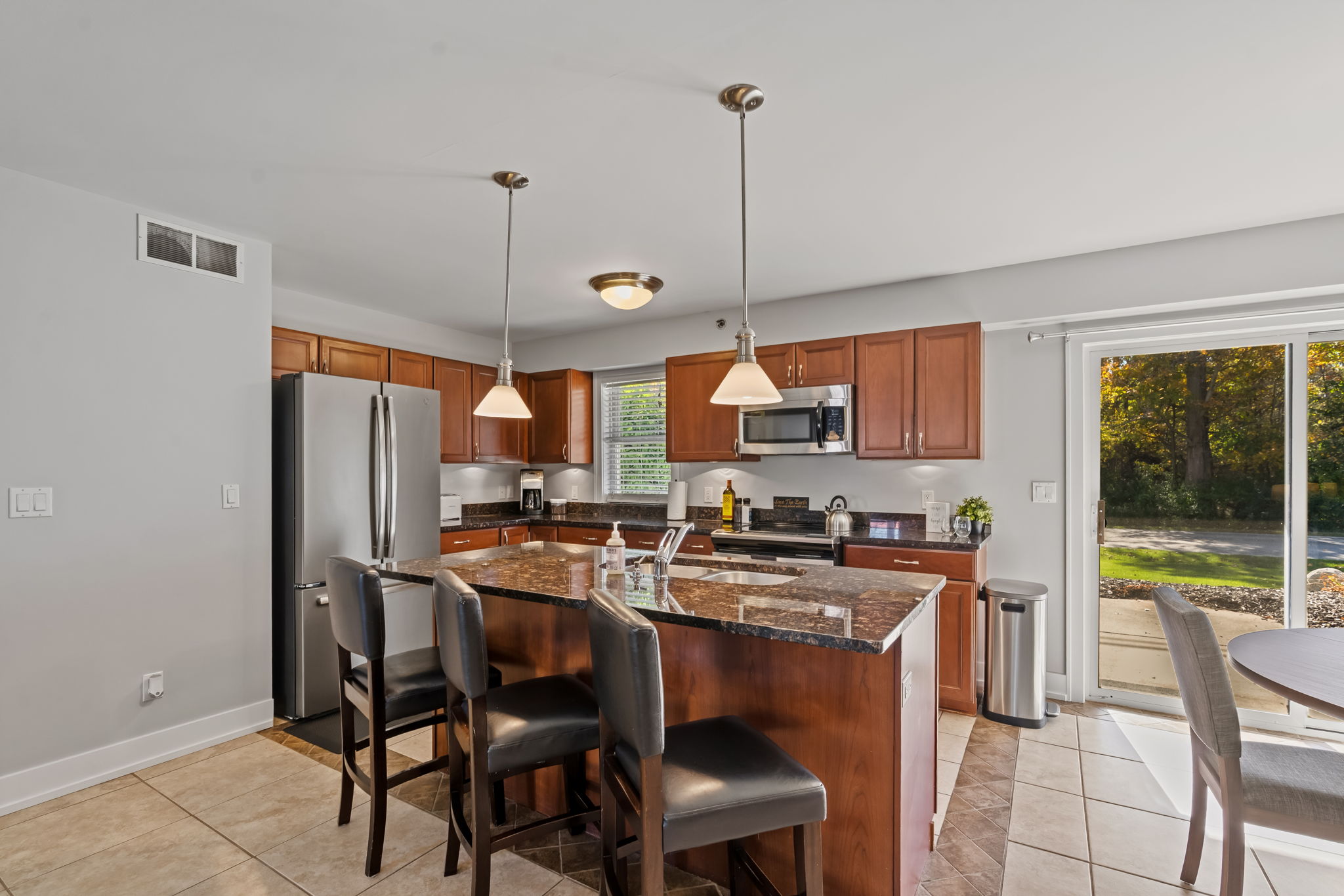 Bright modern kitchen with granite island, bar seating, and patio access