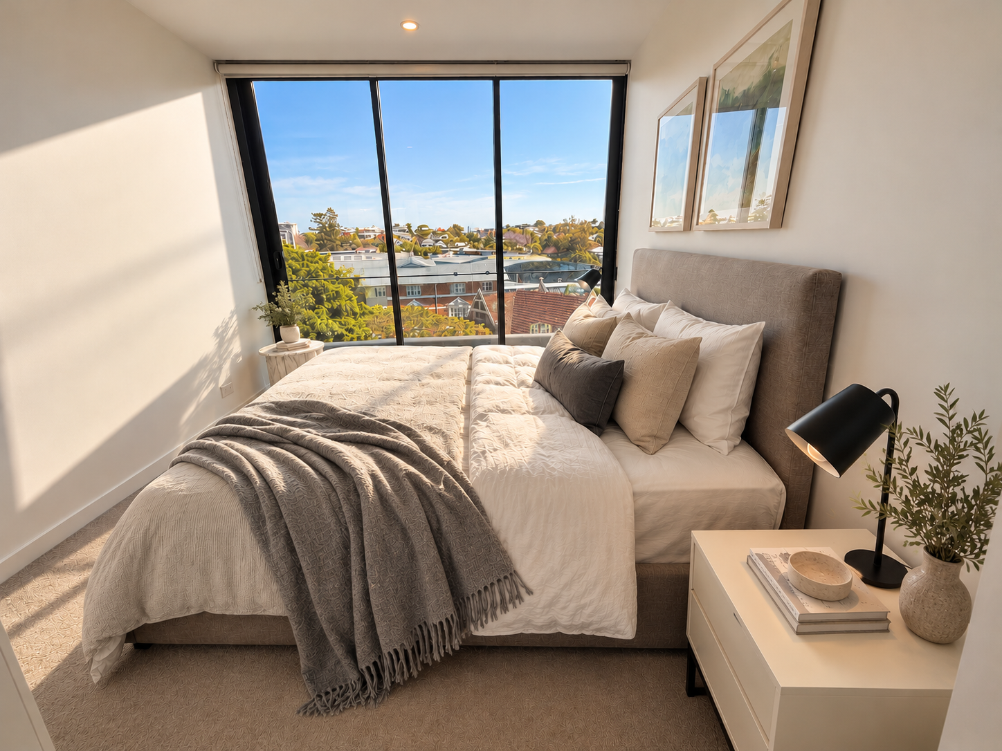 Sunlit bedroom with plush bedding and expansive neighborhood views