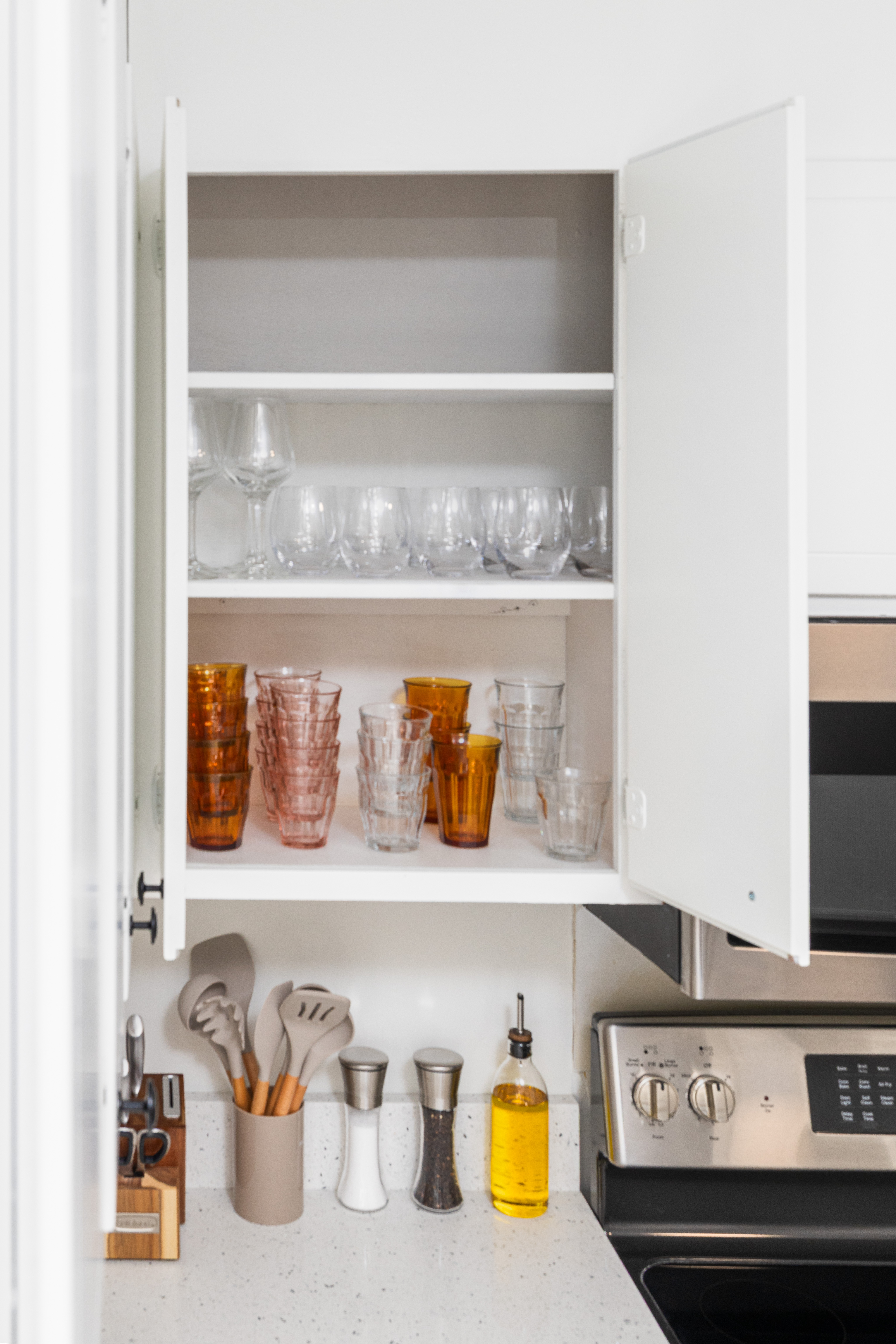 Glassware cabinet with amber tumblers and wine glasses, next to the range