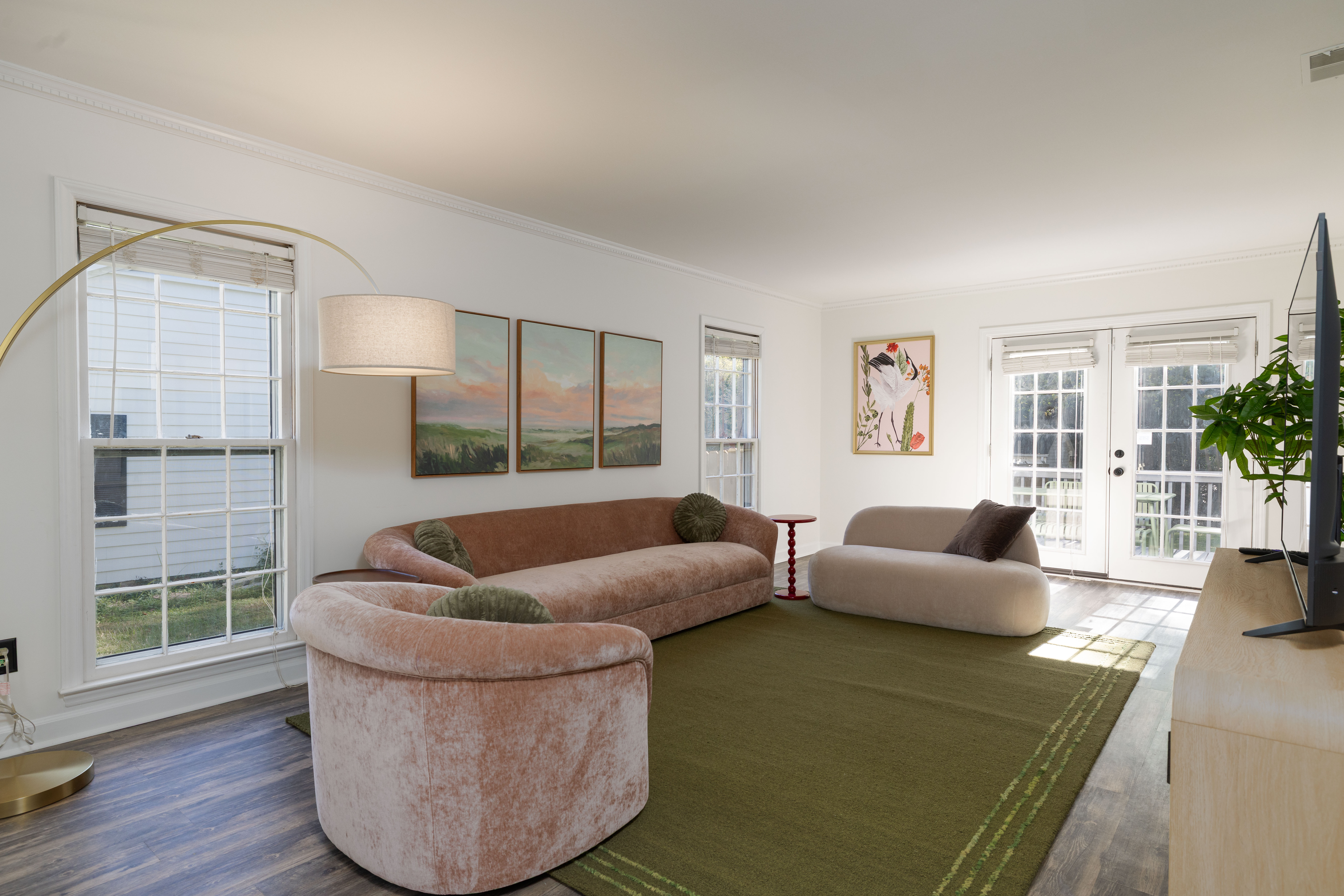 Living room with a curved sofa, armchair and loveseat, and French doors to the deck
