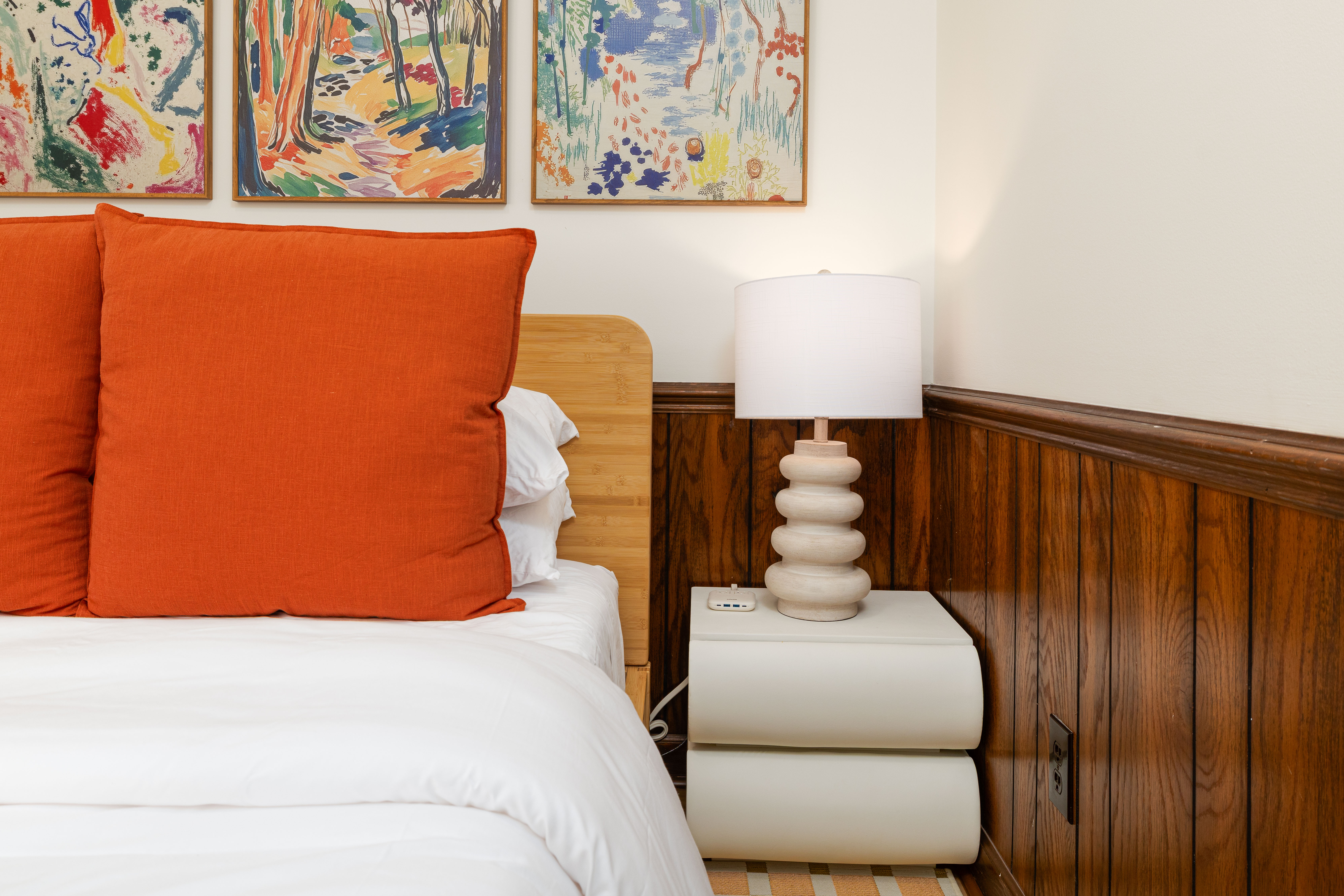 Bedroom 4 (downstairs): queen bed, nightstand and lamp against wood paneling