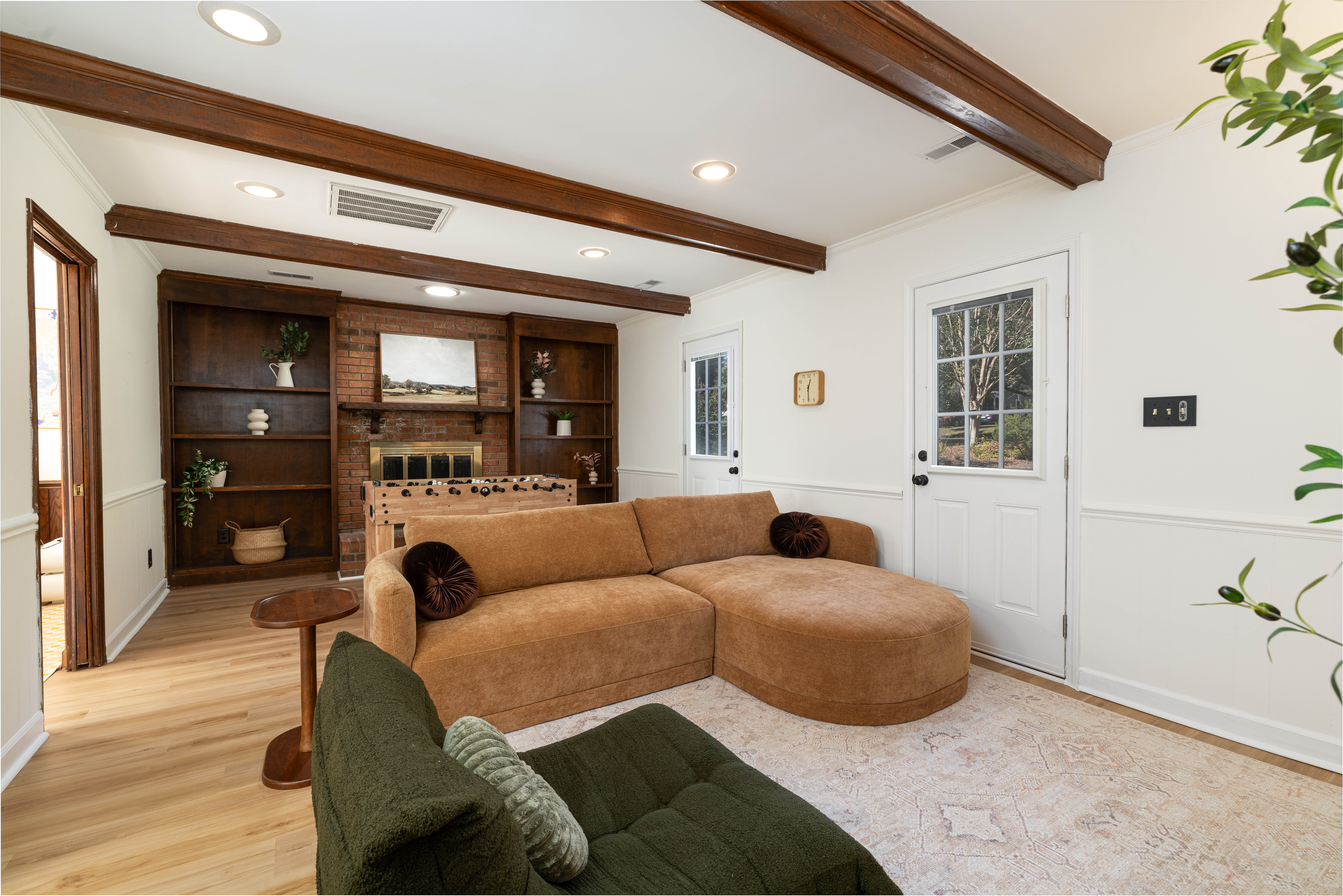 Family room with a deep sectional, built-in shelves and beamed ceiling