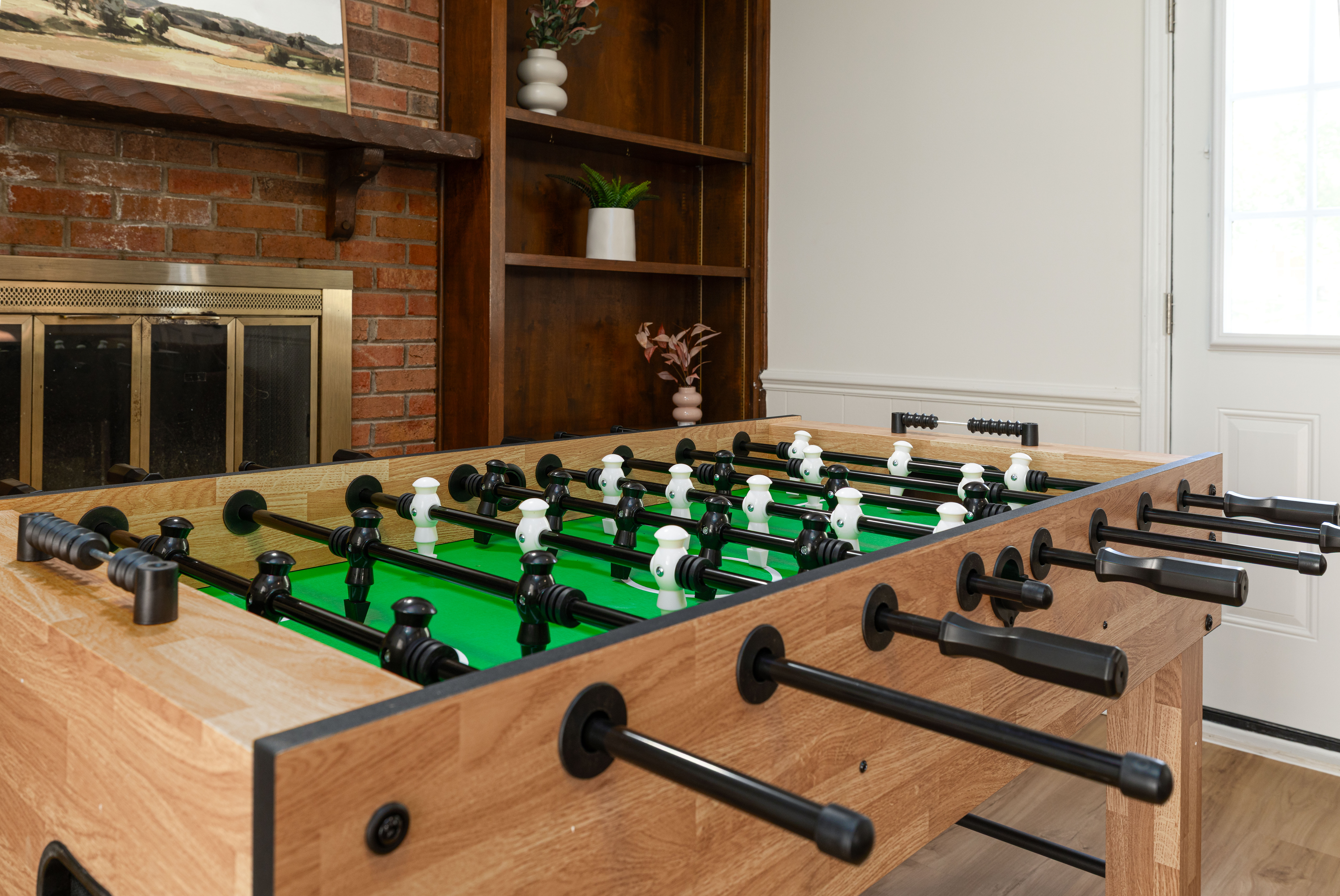 Full-size foosball table in front of the brick fireplace