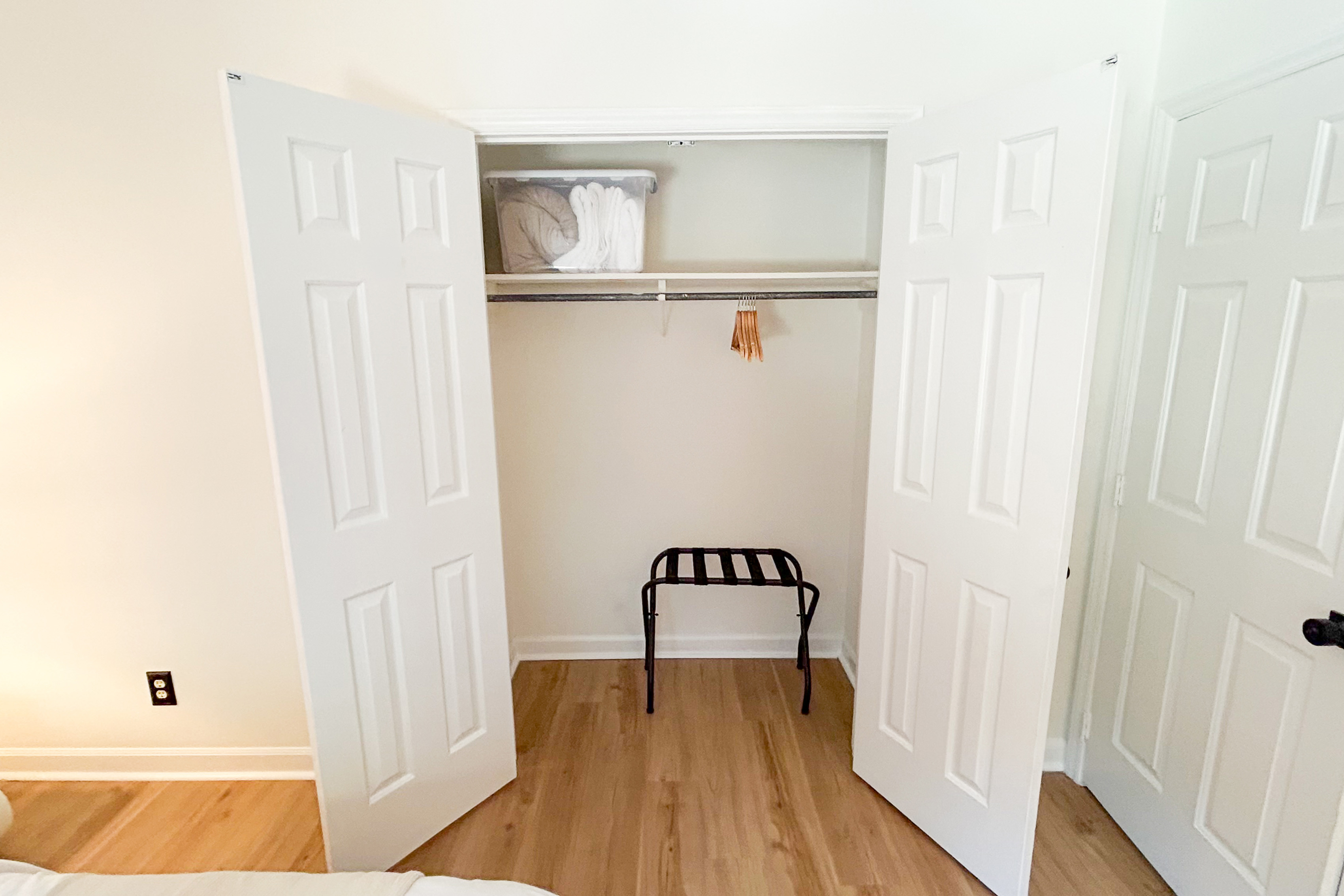 Closet with hangers, a luggage rack and an extra blanket