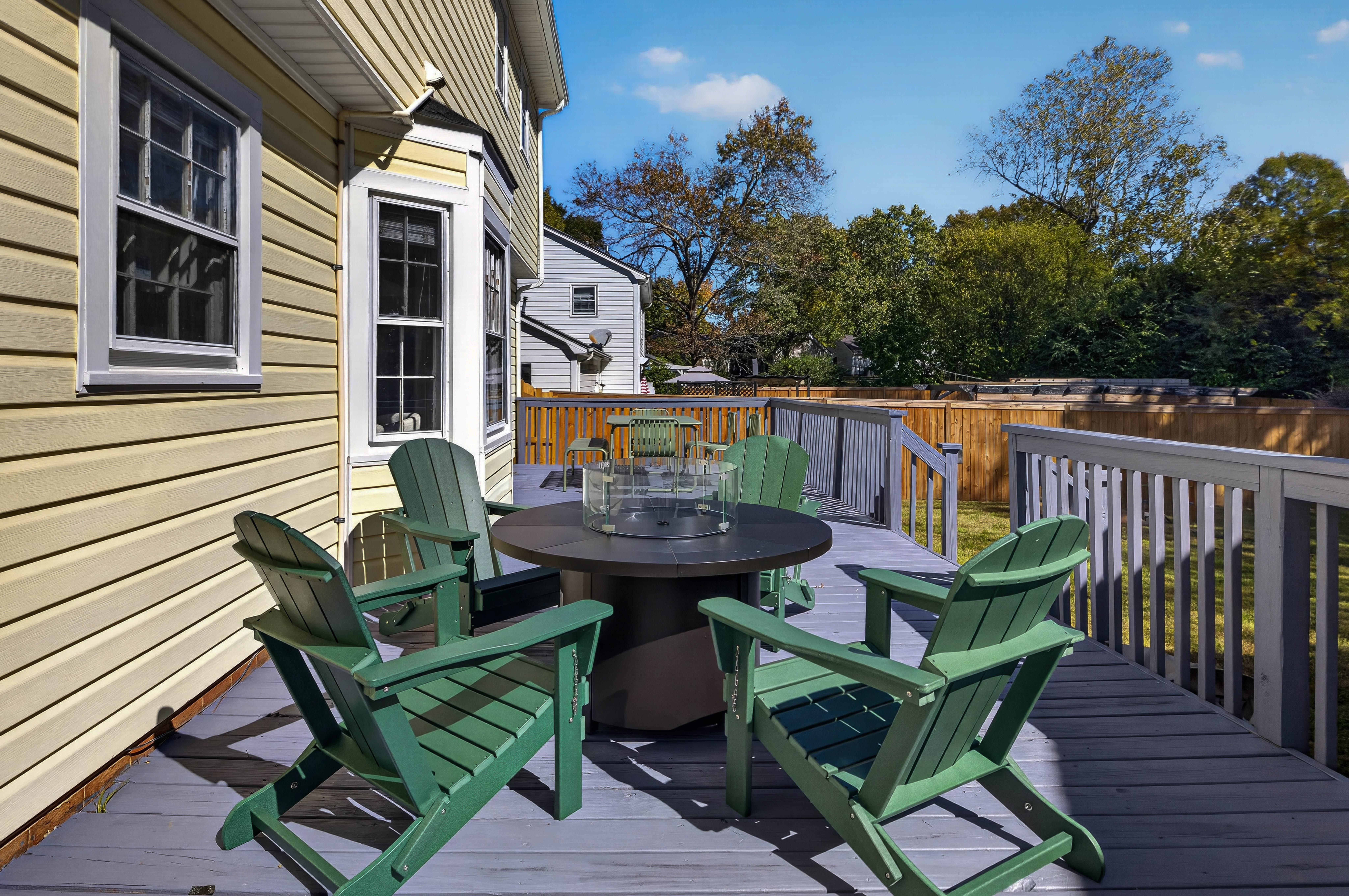 Four Adirondack chairs around the propane firepit on the deck