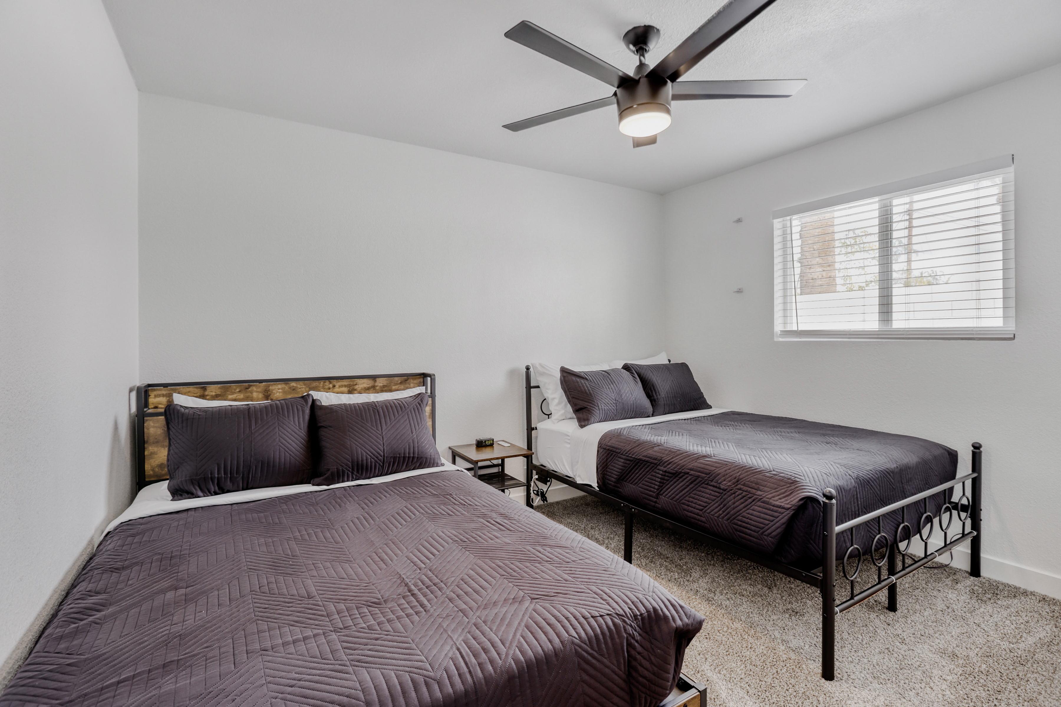 Bright twin-bed room with natural light and a modern ceiling fan