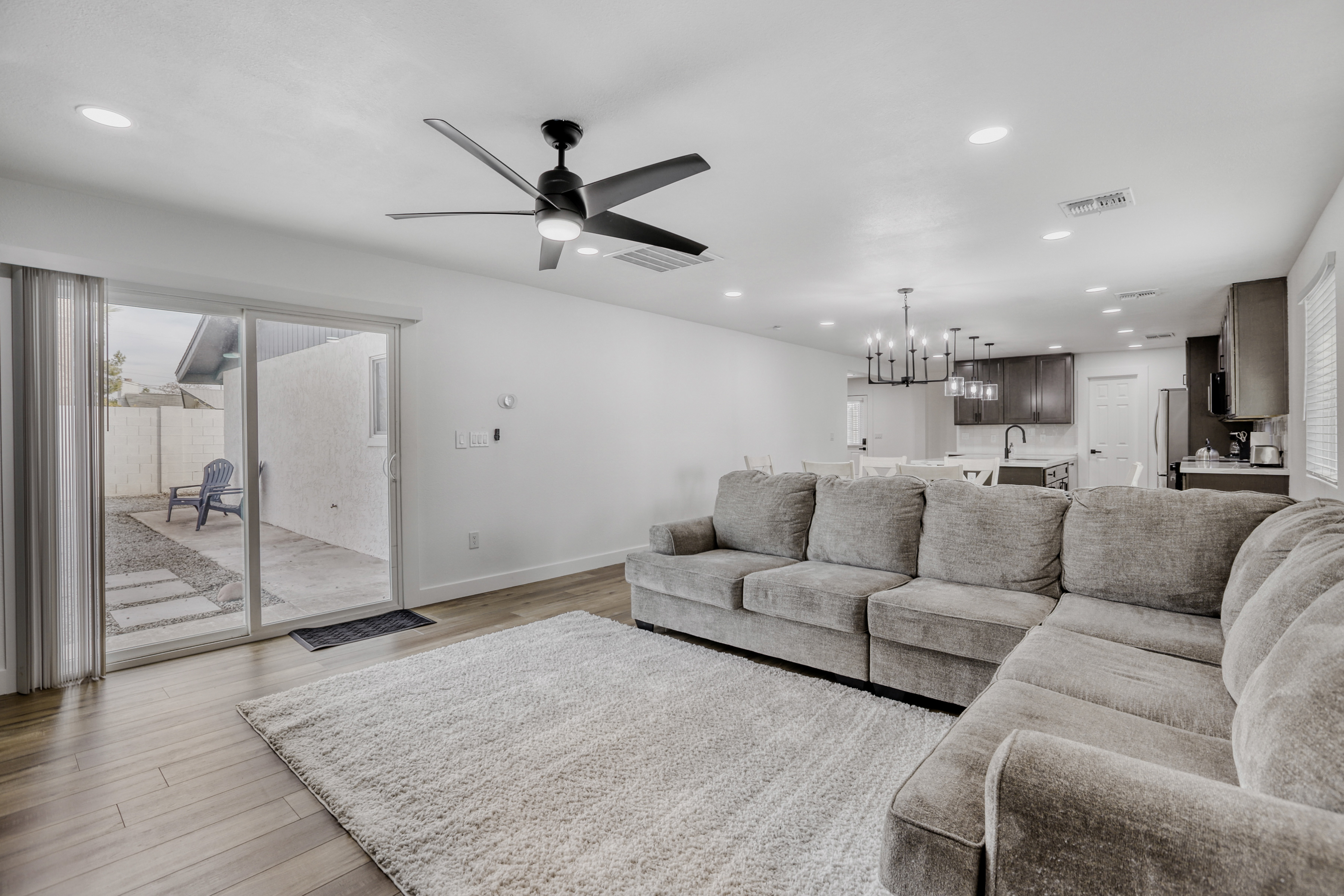 Bright open living room with plush sectional, modern kitchen, and patio access