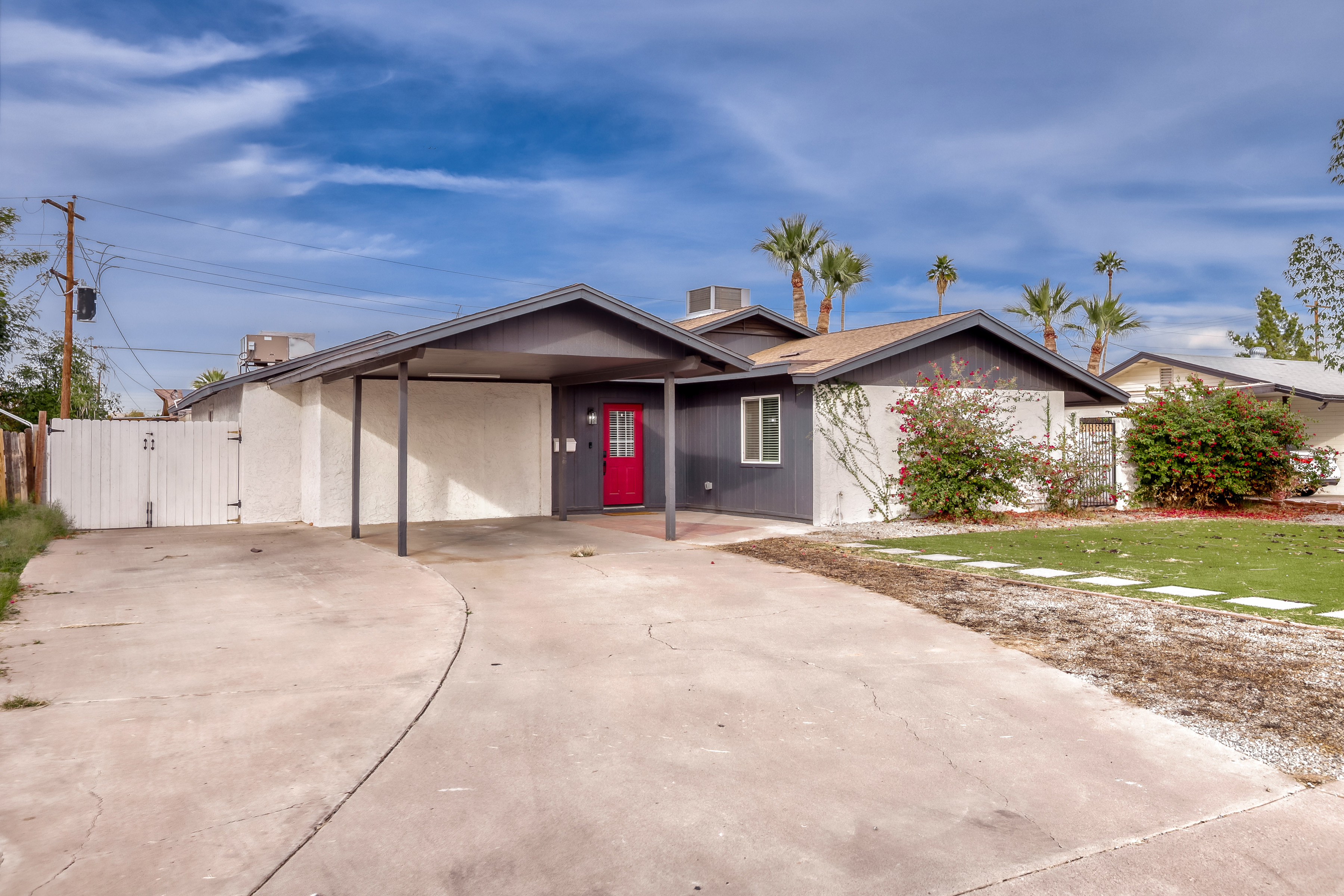 Inviting single-story home with carport, wide driveway, and bold red entry
