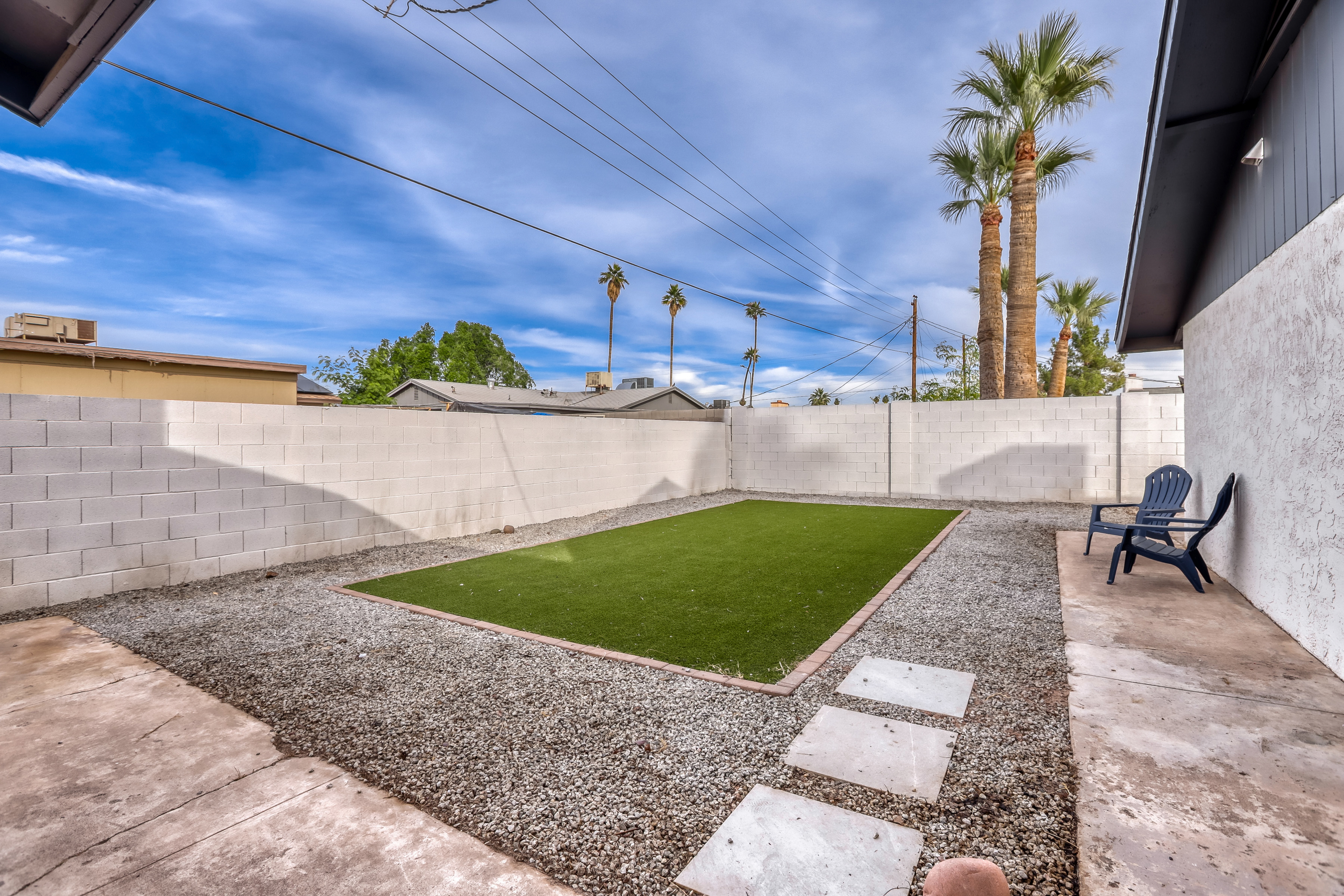 Private backyard with turf lawn, patio seating, and sunny desert vibes