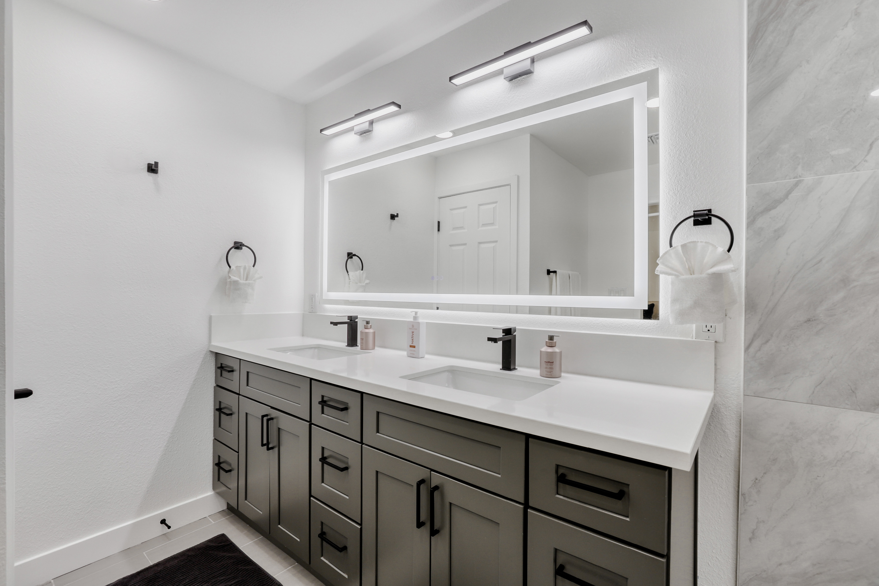 Bright modern double vanity with backlit mirror and spa-like style