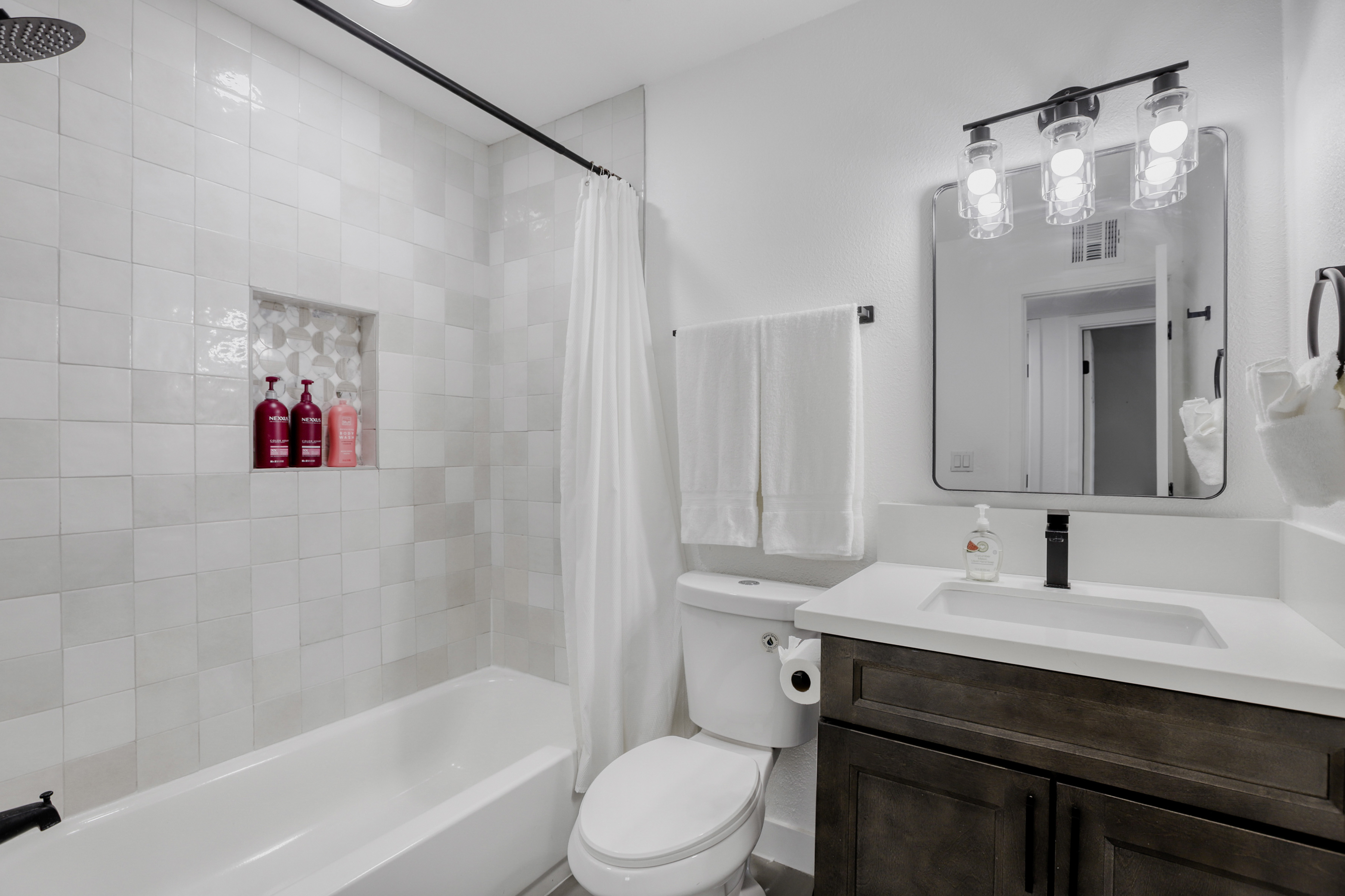 Bright modern bathroom with tiled tub-shower and sleek vanity