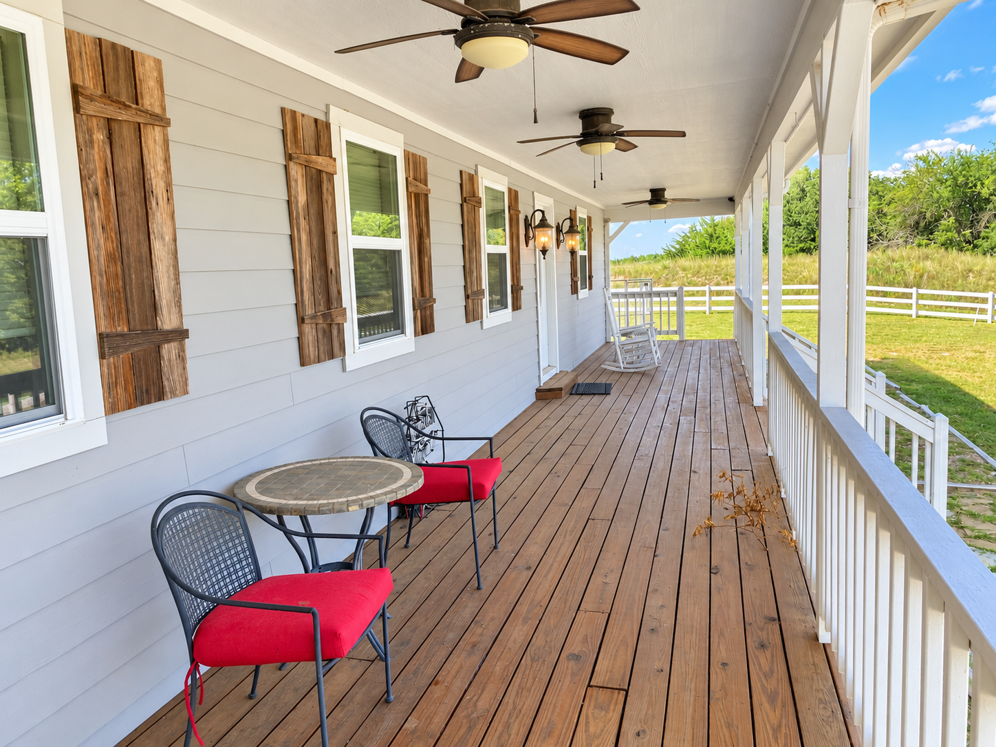 Spacious covered porch with fans, rocking chairs, and serene views