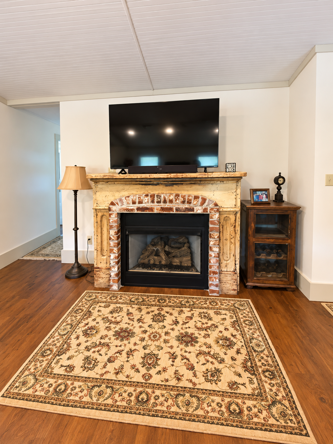 Cozy living space with rustic fireplace, smart TV, and warm hardwood floors
