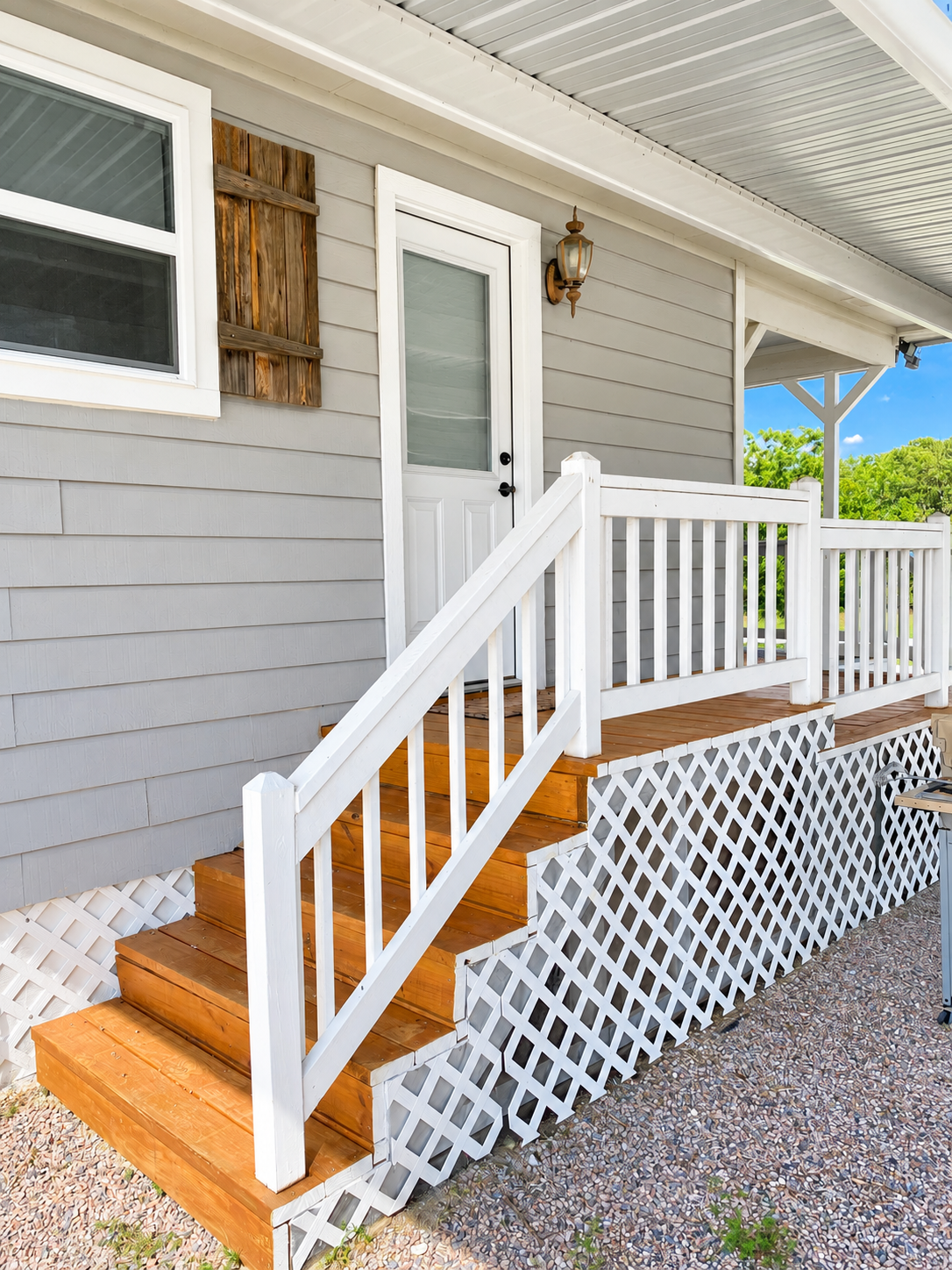 Charming covered porch with warm wood steps and crisp white railings