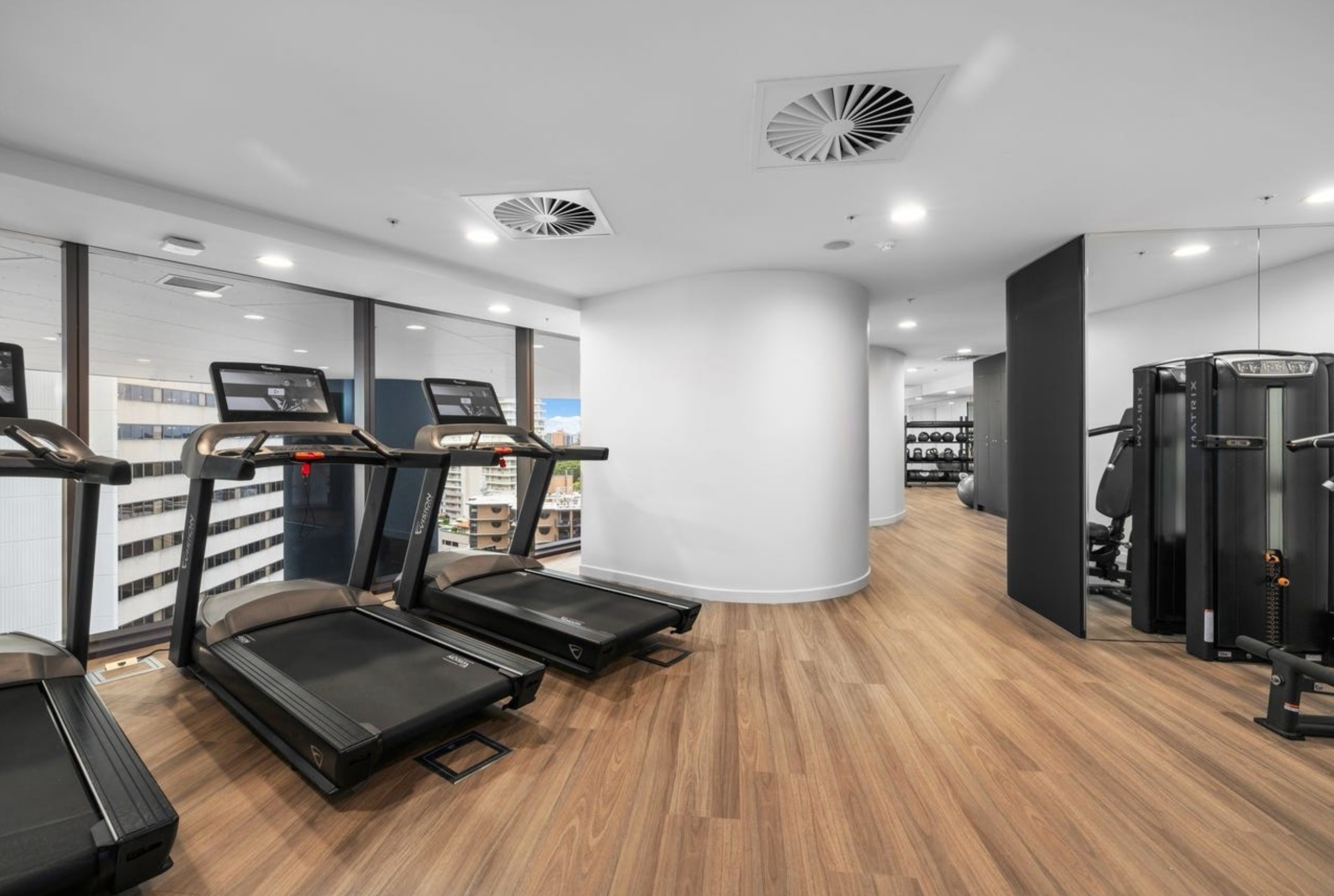 Modern resident gym with treadmills, strength equipment, and city views