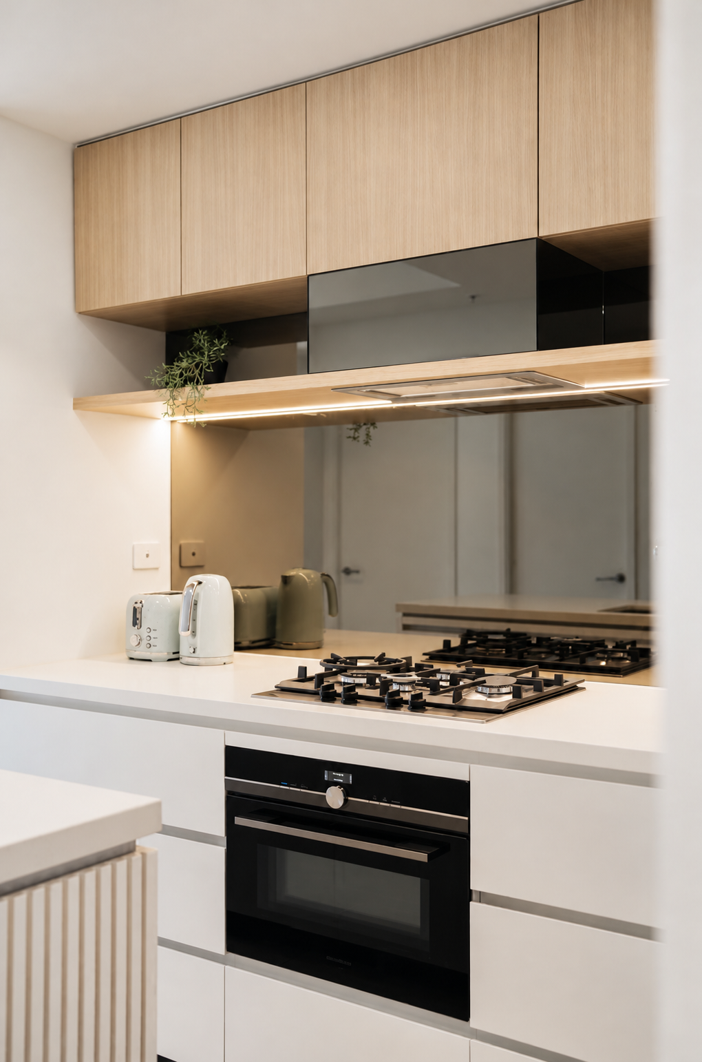 Stylish modern kitchen with gas cooktop, oven, and sleek mirrored backsplash