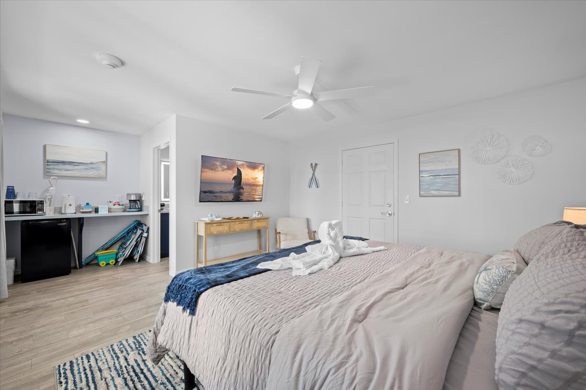 Bright coastal bedroom with TV, kitchenette nook, and comfy king bed