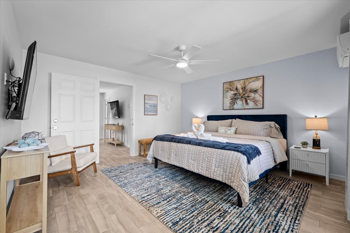 Bright, spacious king bedroom with TV, seating, and coastal-style decor