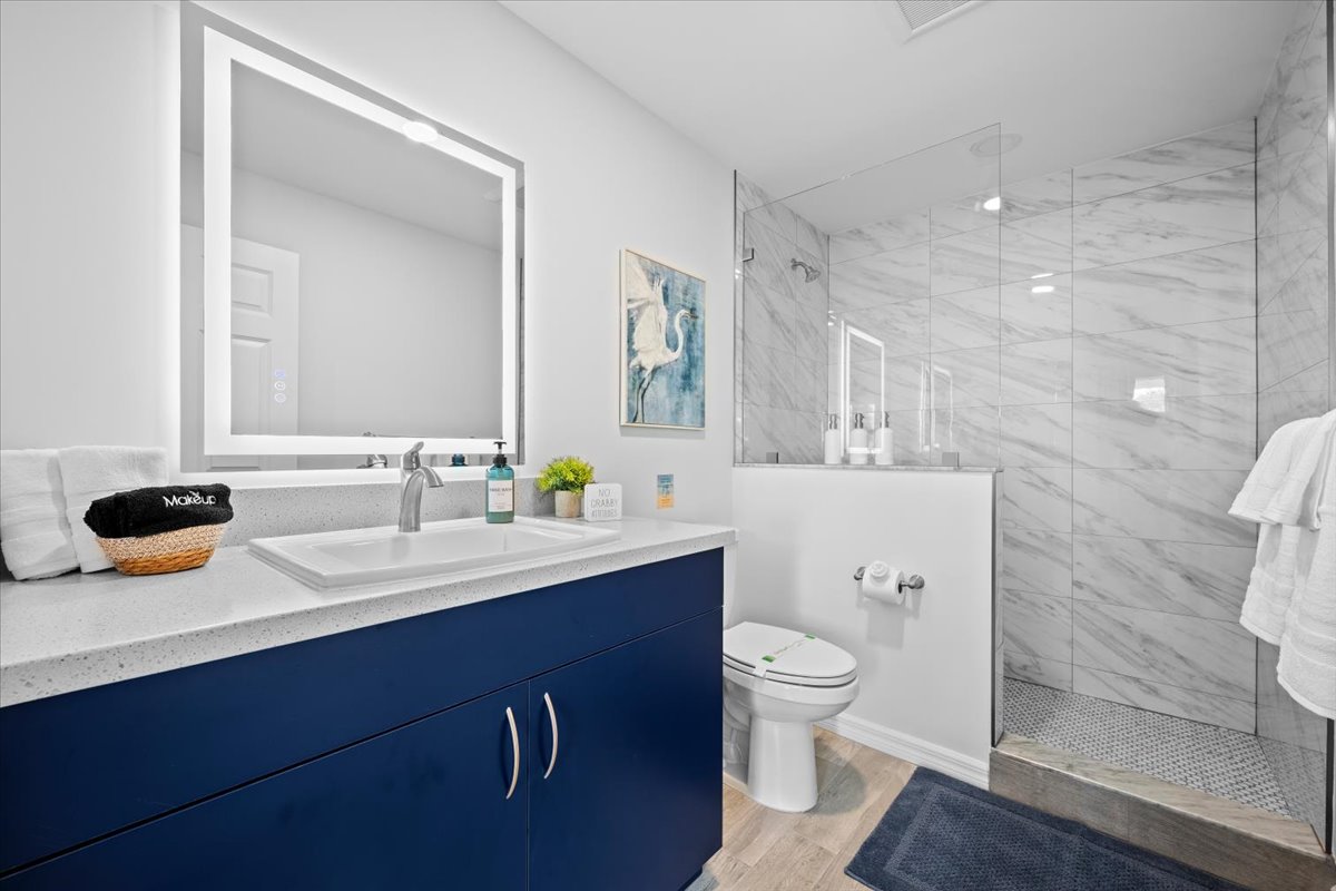 Modern spa-like bathroom with glass walk-in shower and illuminated mirror