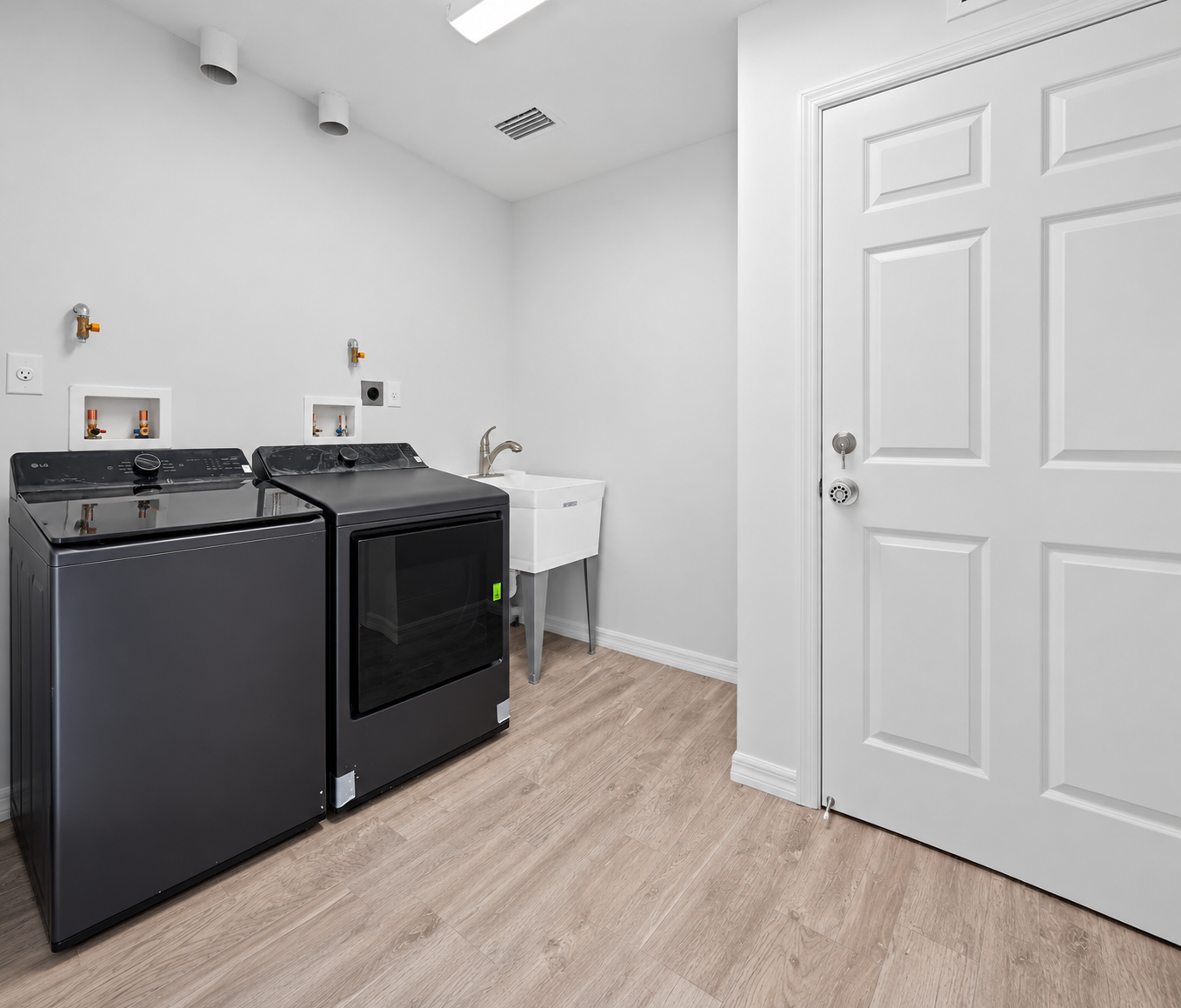Bright modern laundry room with washer, dryer, and utility sink