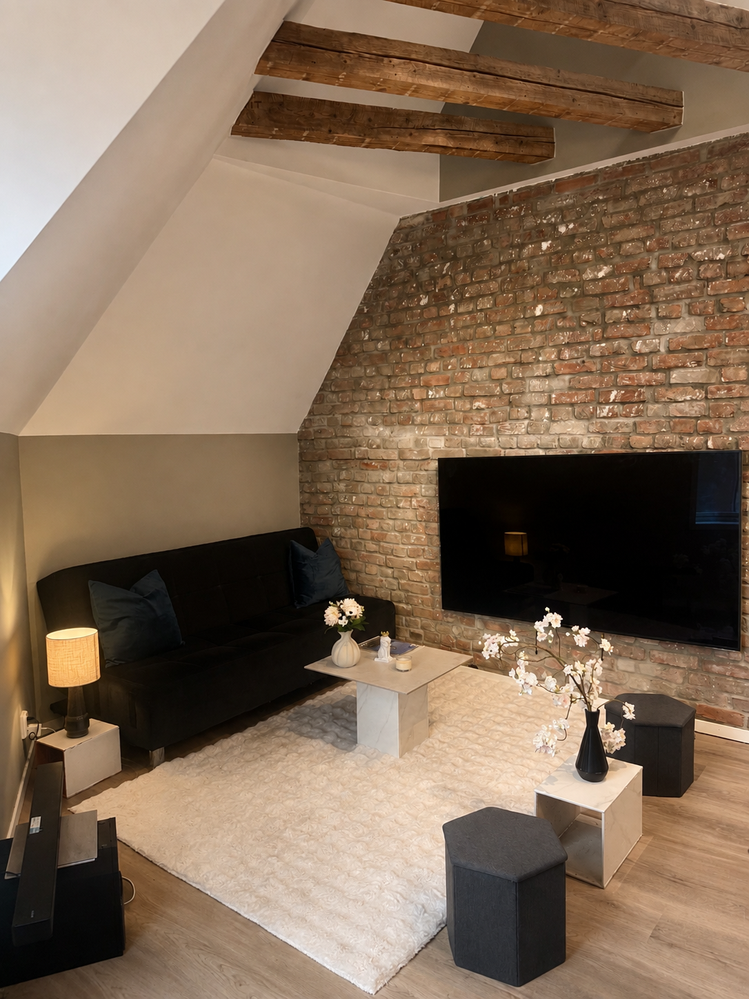 3-floor Cozy loft lounge with exposed brick, wood beams, and a large TV