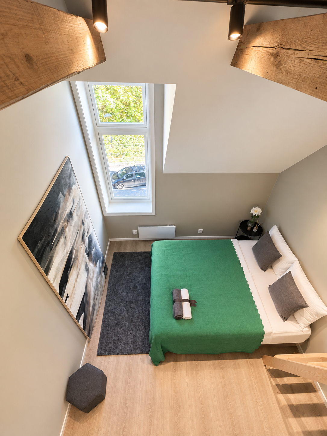 Bright loft bedroom with skylight, exposed beams, and stylish modern decor
