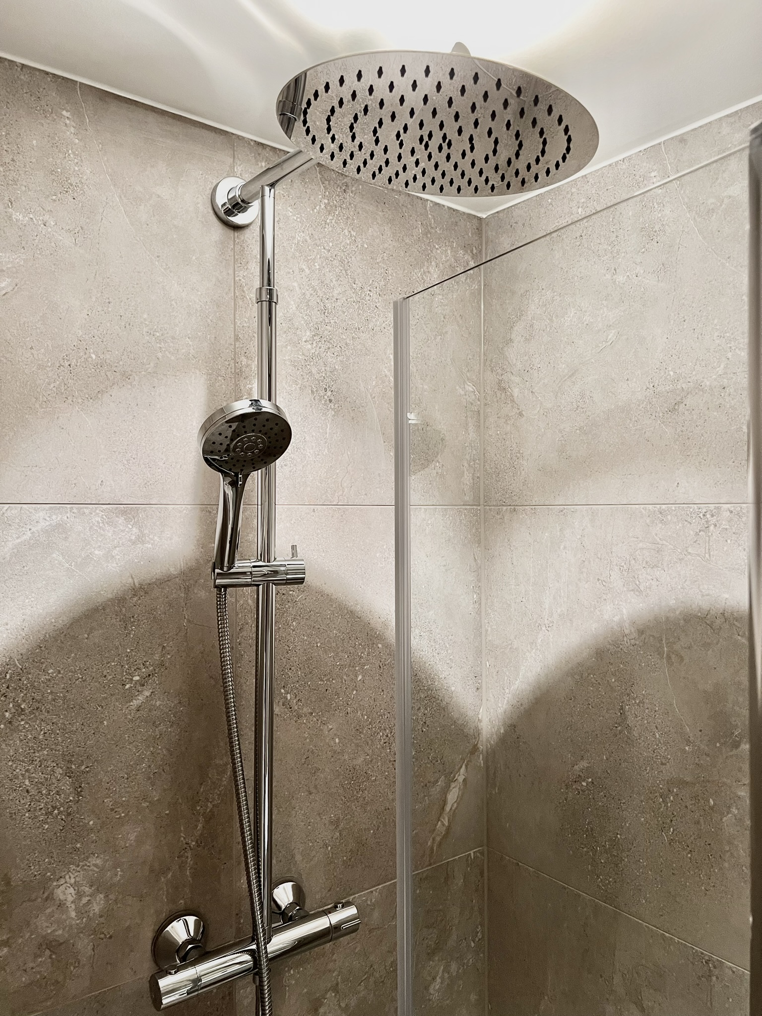 Spa-style walk-in shower with rainfall head and modern stone tile