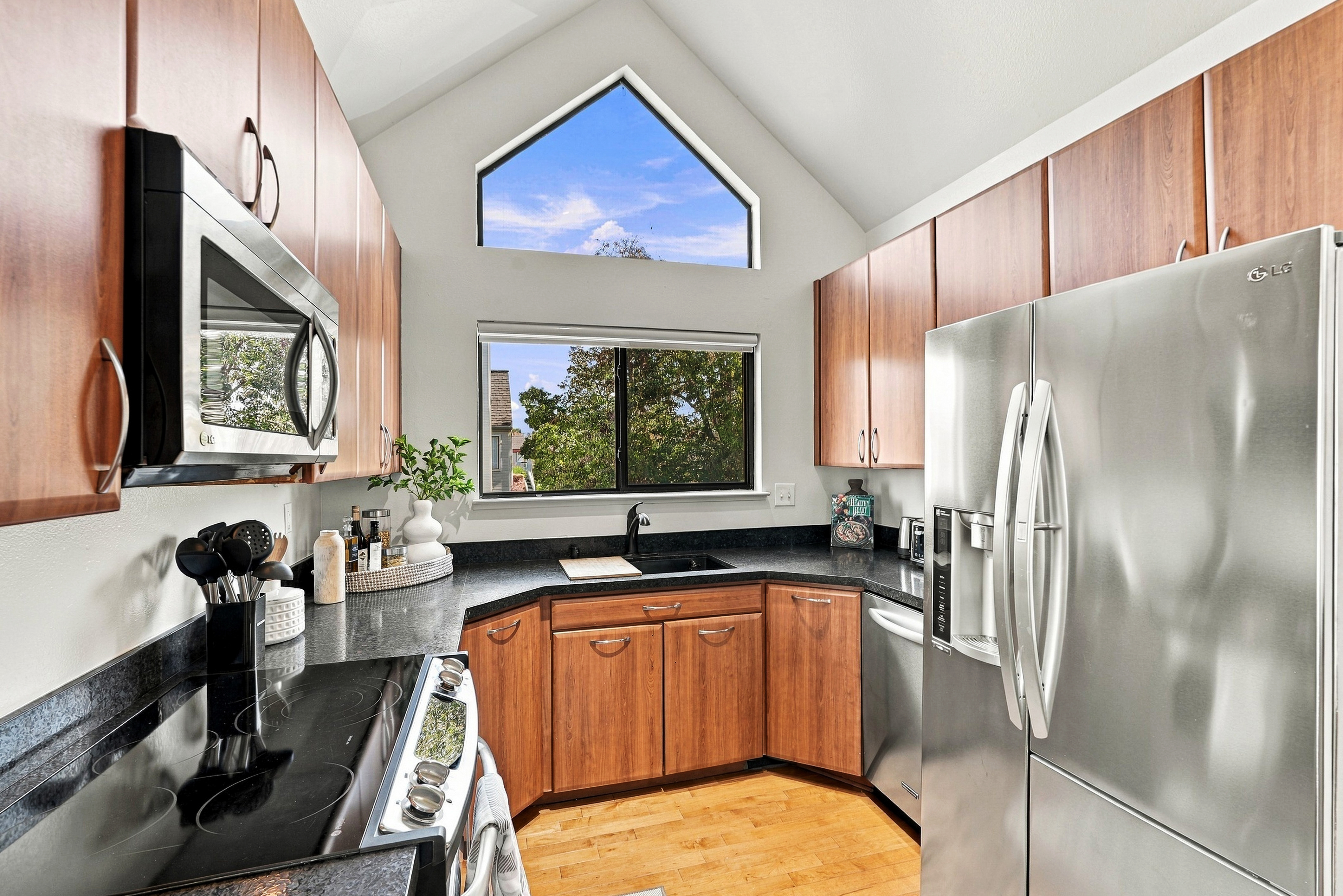 Bright vaulted kitchen with stainless appliances and treetop views